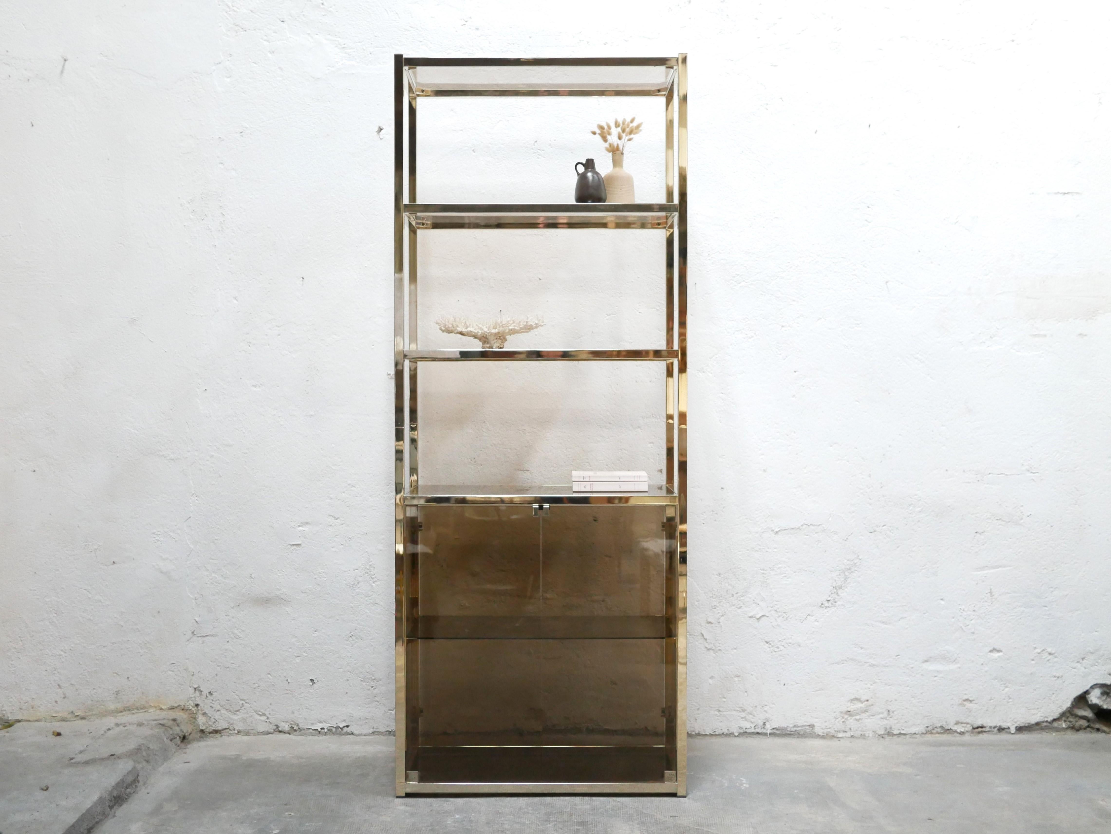 Bookcase in brass and smoked glass from the 70s.

Its sculptural geometric shape gives it a lot of elegance, character and refinement.
Of good size, it offers a large storage space.

Good condition, some marks of time, in particular the brass