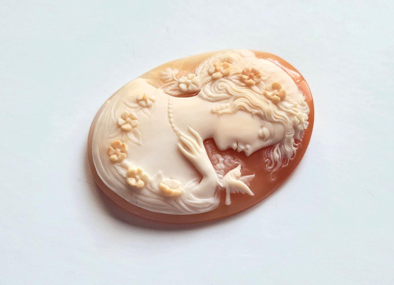 This vintage unmounted Carnelian shell cameo depicting the profile of the beautiful young lady with a little bird is very well carved in exquisite detail. This cameo dates back to around the 1930s-1940s.
The carving on this cameo is excellent and