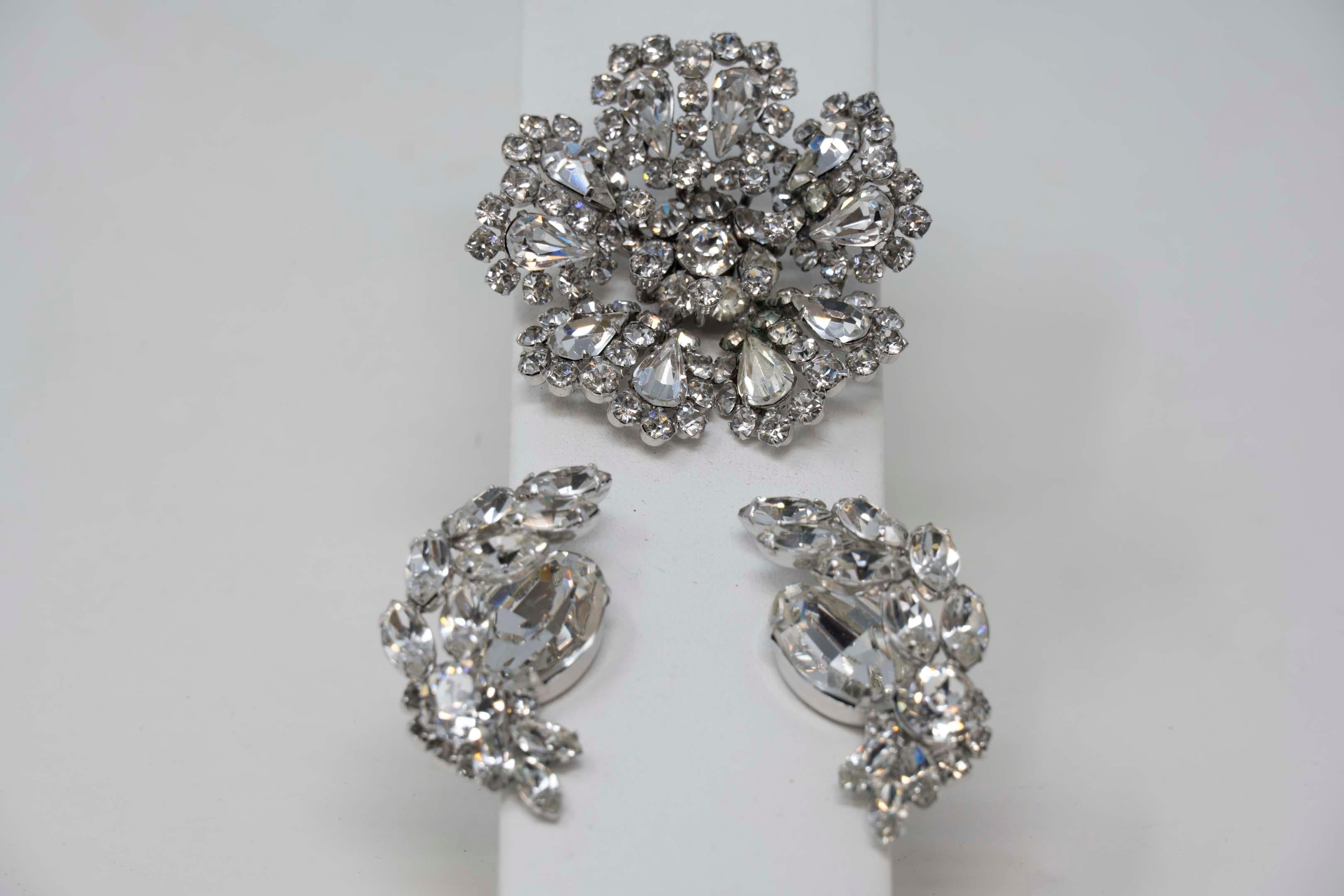 Signed demi parure clear rhinestone brooch matching earrings mid century, brooch 2 inches in diameter, earrings 1 /58 inches long. Crystal in good condition.
