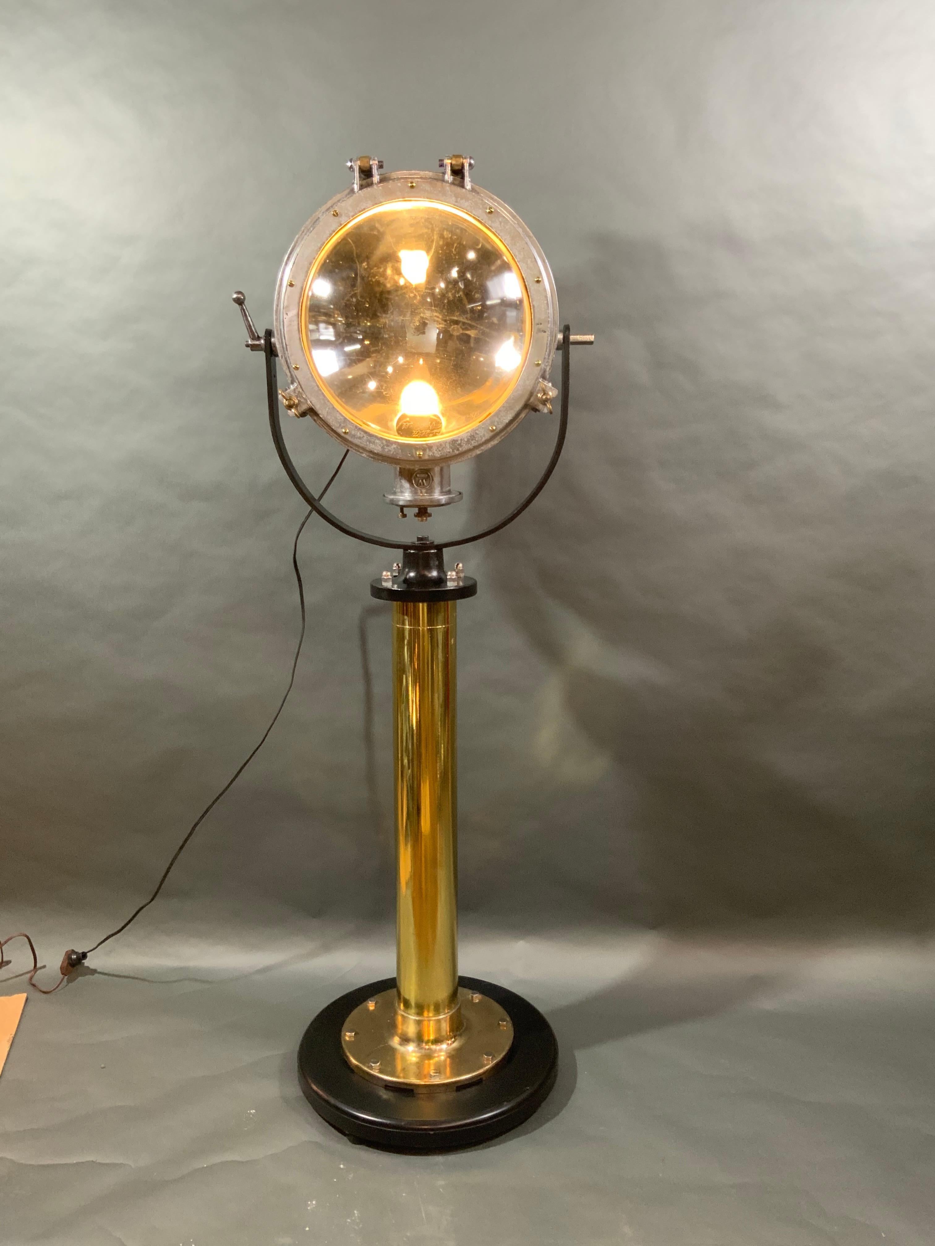 Industrial lighting piece of vintage lighting. Ships spotlight which is mounted by an iron yoke onto a brass pedestal. Rewired with an electric socket. Weight is 107 pounds. Dimensions are 69 inches tall and 20 inch diameter. Price $3495.