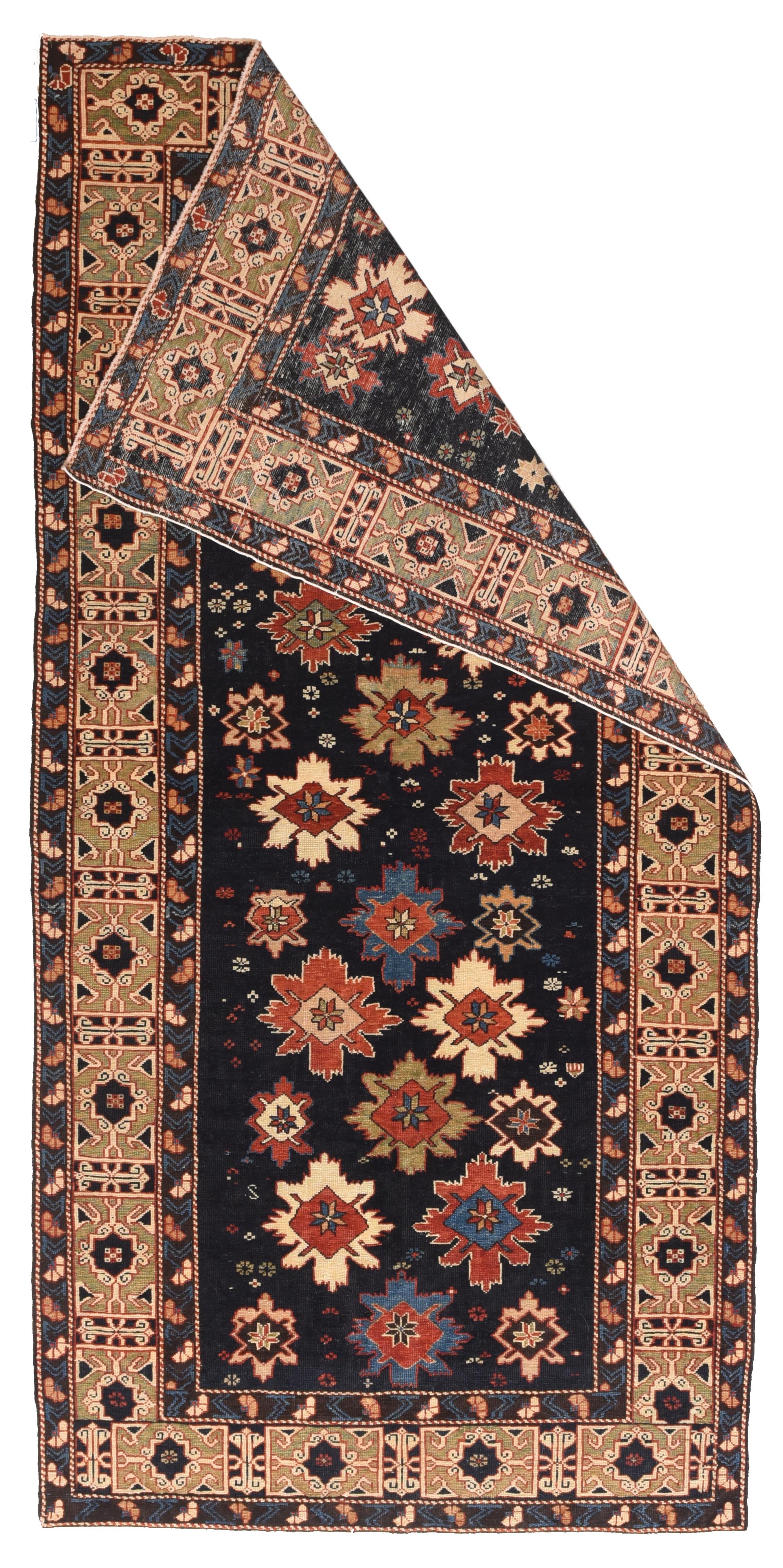 This is one of the most iconic of Caucasian rug patterns. The nearly navy field hosts a fall of “snowfakes” in reds, blues, ivory and khaki. making a subtle diagonal over-patterns. Stars and smaller geometric forms are sprinkled about. Khaki main