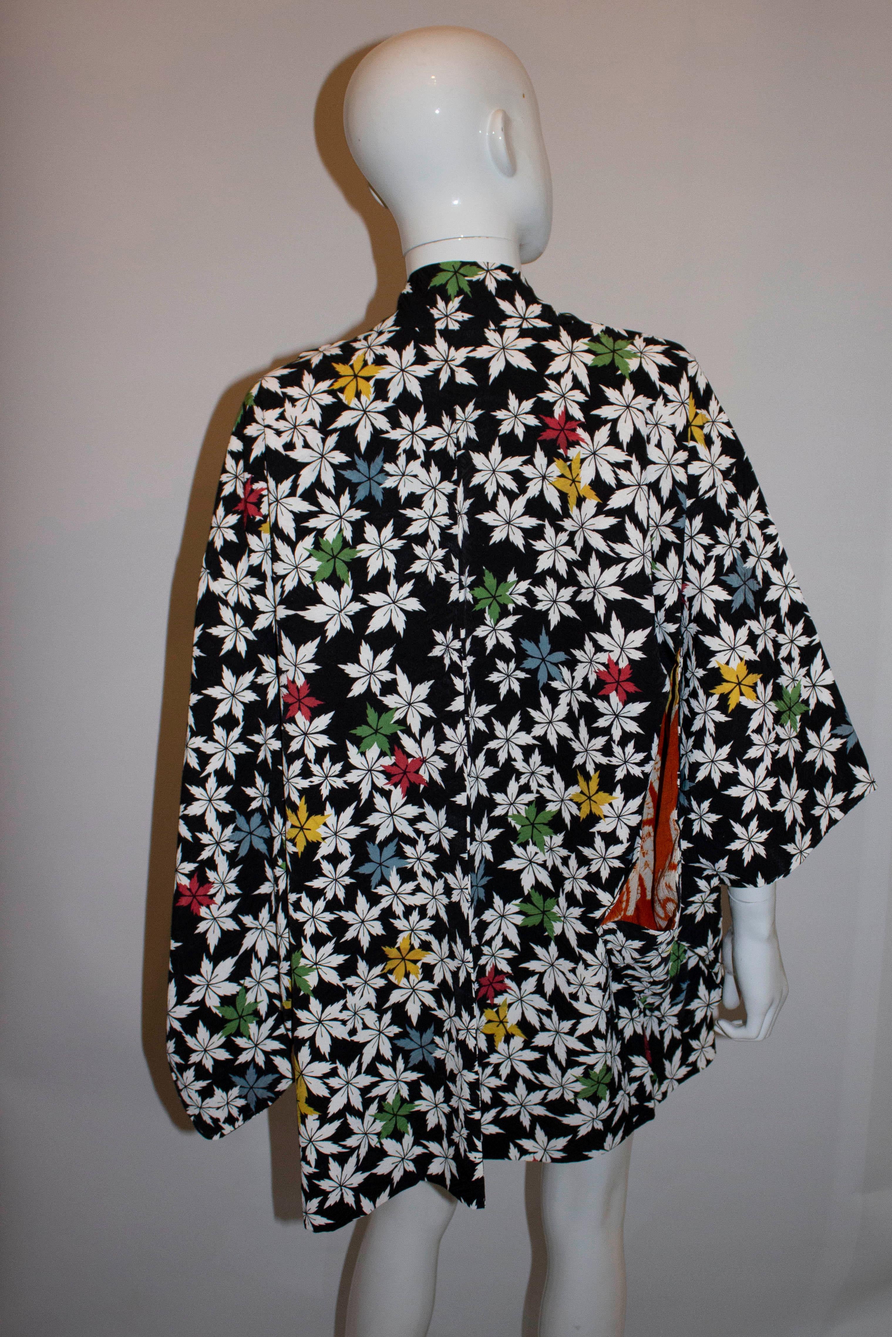 A head turning vintage short kimono , with a black background and multicolour leaf design. The kimono has a rust colour lining in the top half. Measurements : Bust up to 42'', length 32''