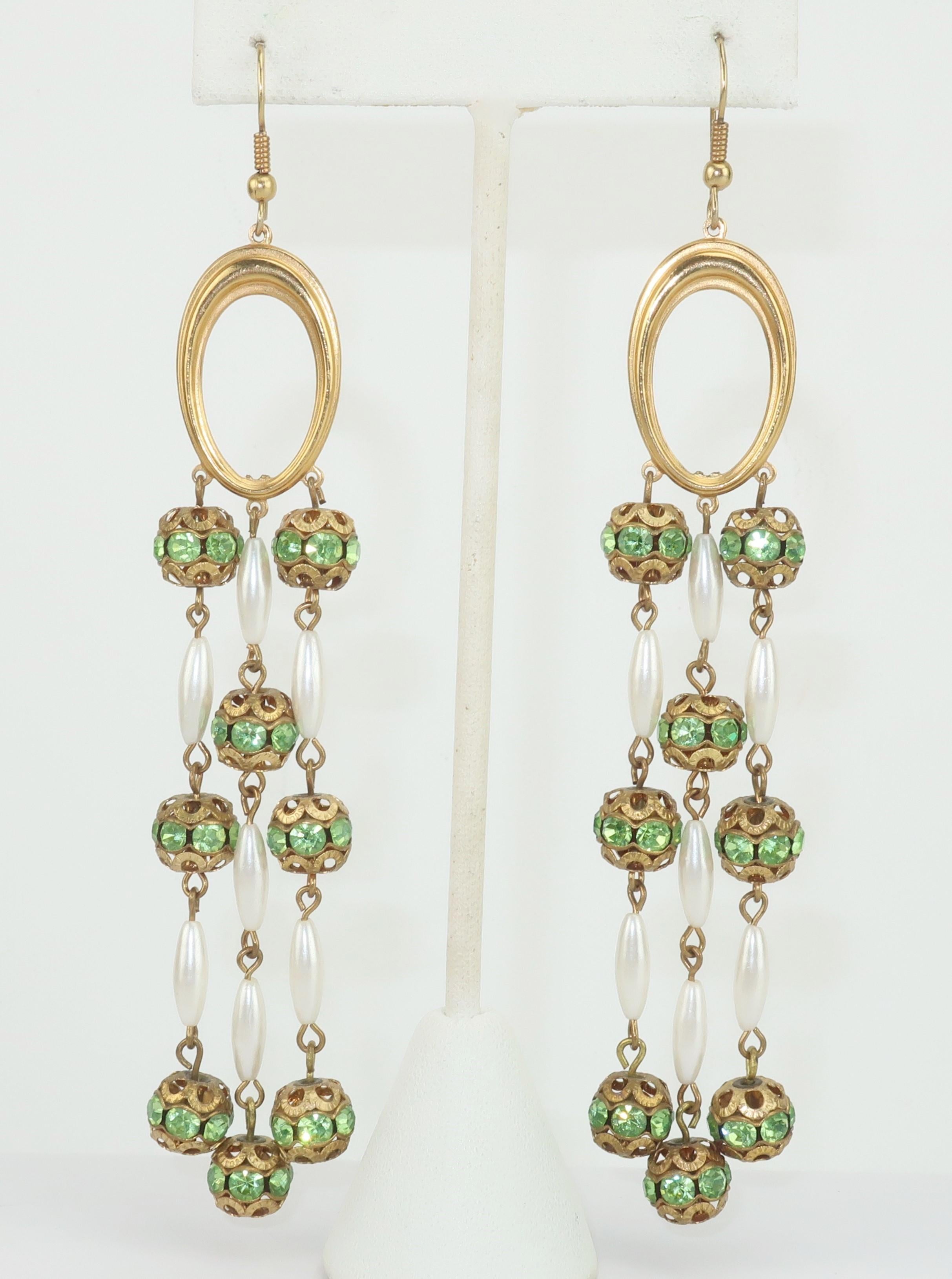 A super long pair of chandelier earrings are the perfect way to add a touch of glamour to your look.  These danglers consist of an oval gold tone hoop base with strands of filigree beads embellished with green rhinestones and mixed with pearl beads.