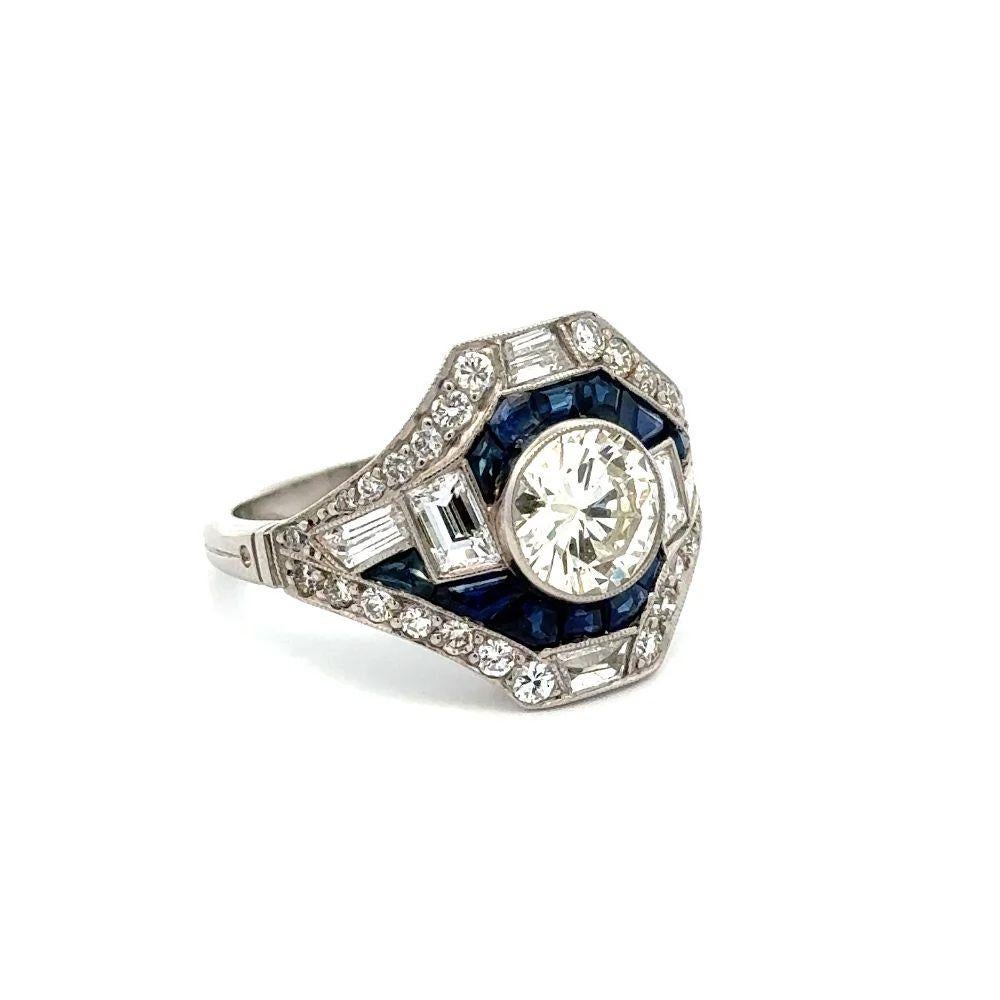 Simply Beautiful! Finely detailed Diamond and Blue Sapphire Statement Platinum Ring. Centering a securely nestled Hand set 1.20 Carat Transitional Diamond and Blue Sapphire, accented with Baguette & RBC Diamonds, weighing approx. 1.12tcw. Hand