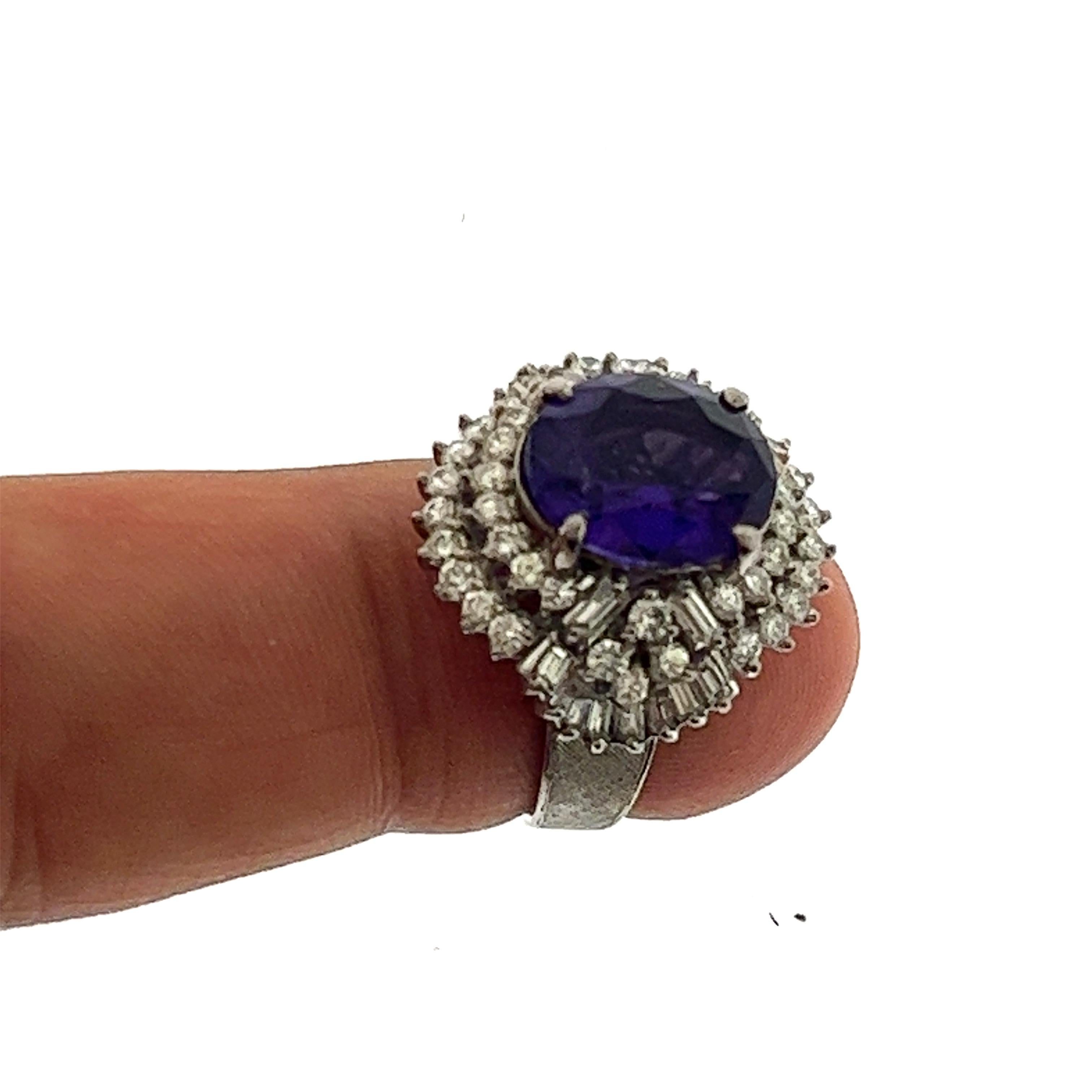 Offered here is natural earth mined Siberian Amethyst, centered in a vintage diamond ballerina ring, circa Retro period 1950-60.
Amethyst has a rich noble purple color with top clarity, measuring approximately 12.30mm by 10.20mm weighing about 4
