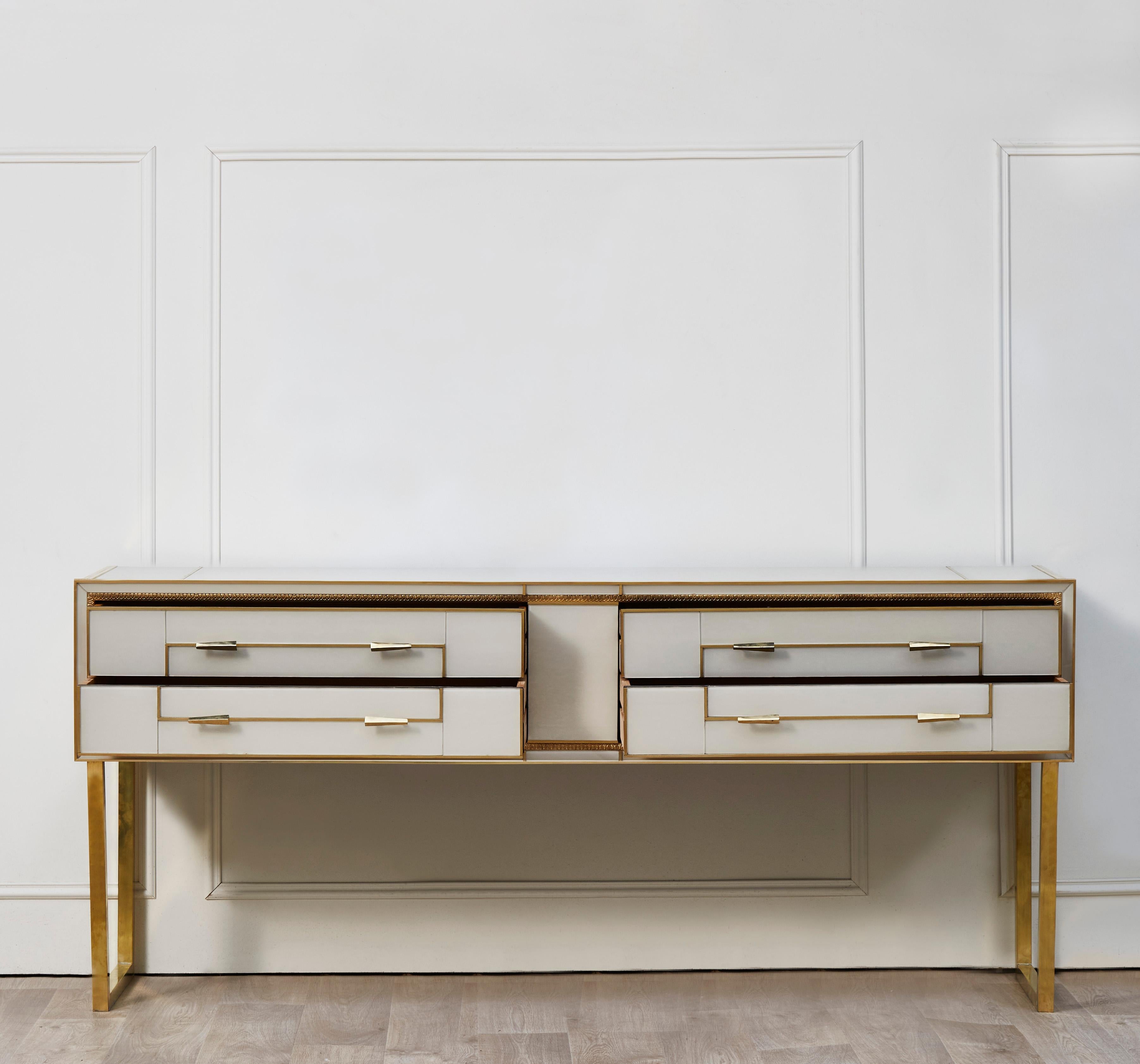 Exceptional wooden sideboard entirely restored and customized with ivory-coloured mirrors and brass inlays. 4 drawers and 2 brass feet.
Italy, 1980s.