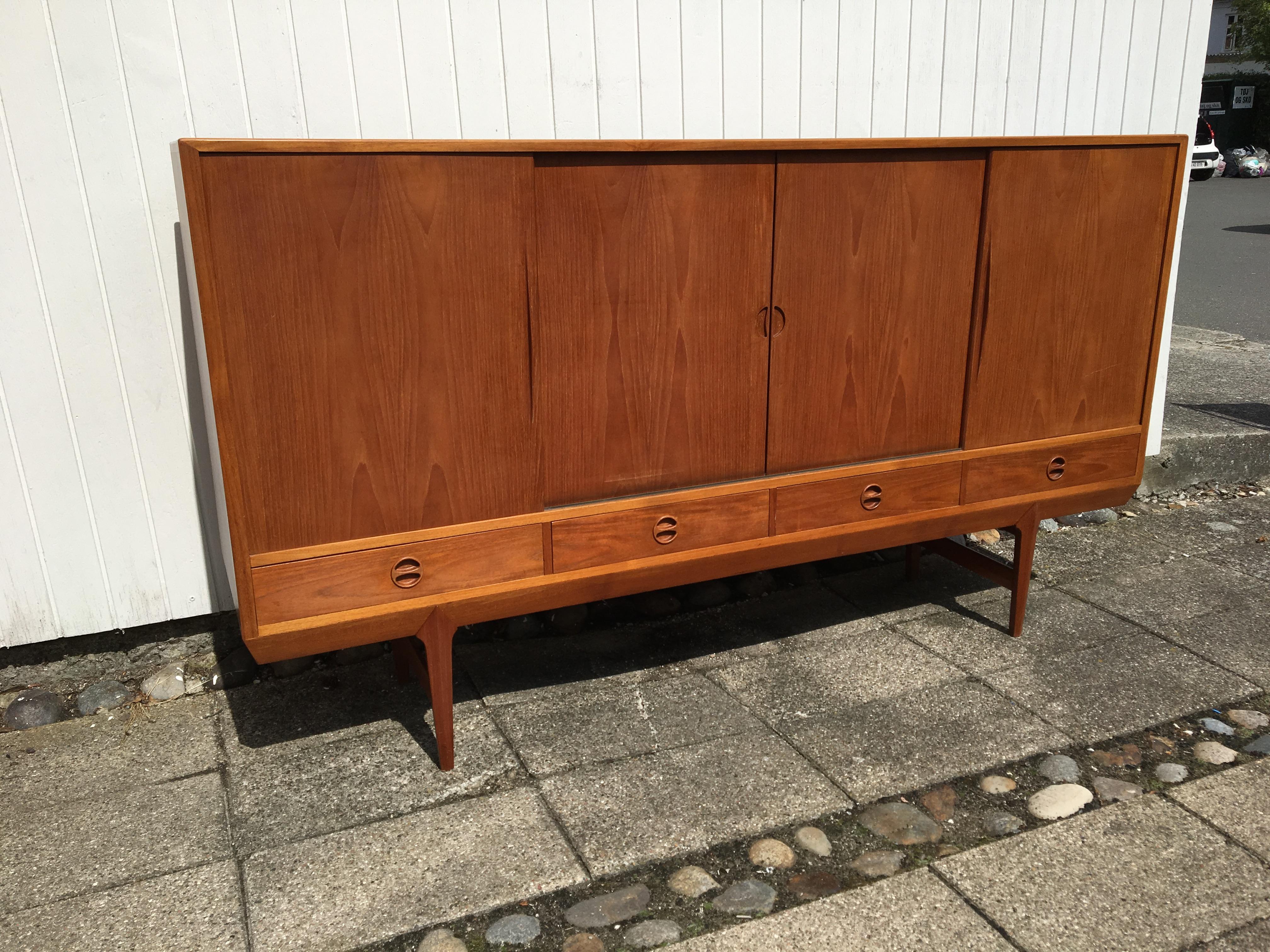 Teak sideboard with sliding doors and 4 drawers. 
The sideboard is in original condition and has a ring on top. 
The sideboard is with unknown designer. 
Dimensions: 200 x 111 x 44 cm.