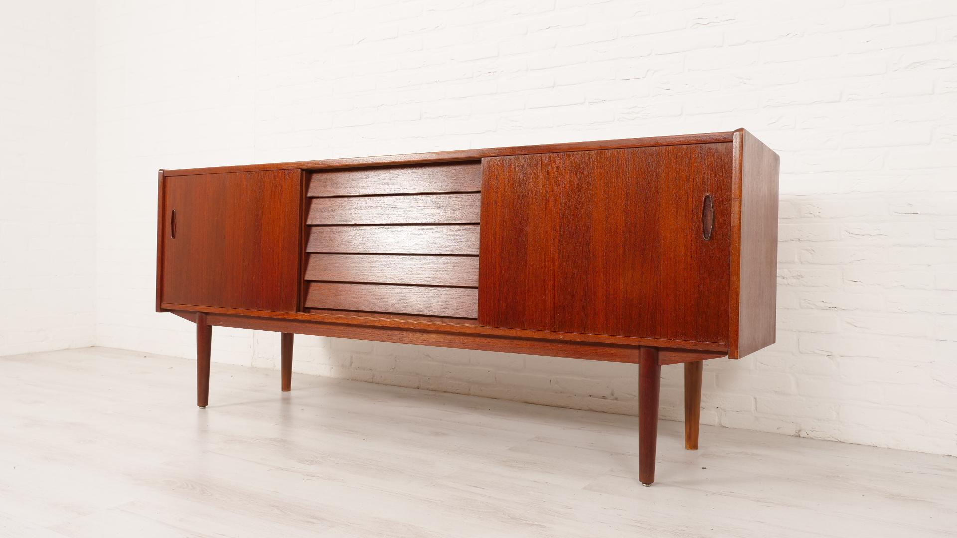 A truly beautiful sideboard by Hugo Troeds, designed by Nils Jonsson in the 1950s, this stylish sideboard comes from Sweden. The vintage sideboard has 2 sliding doors that slide very smoothly. In the middle, it has 5 drawers designed with dovetail
