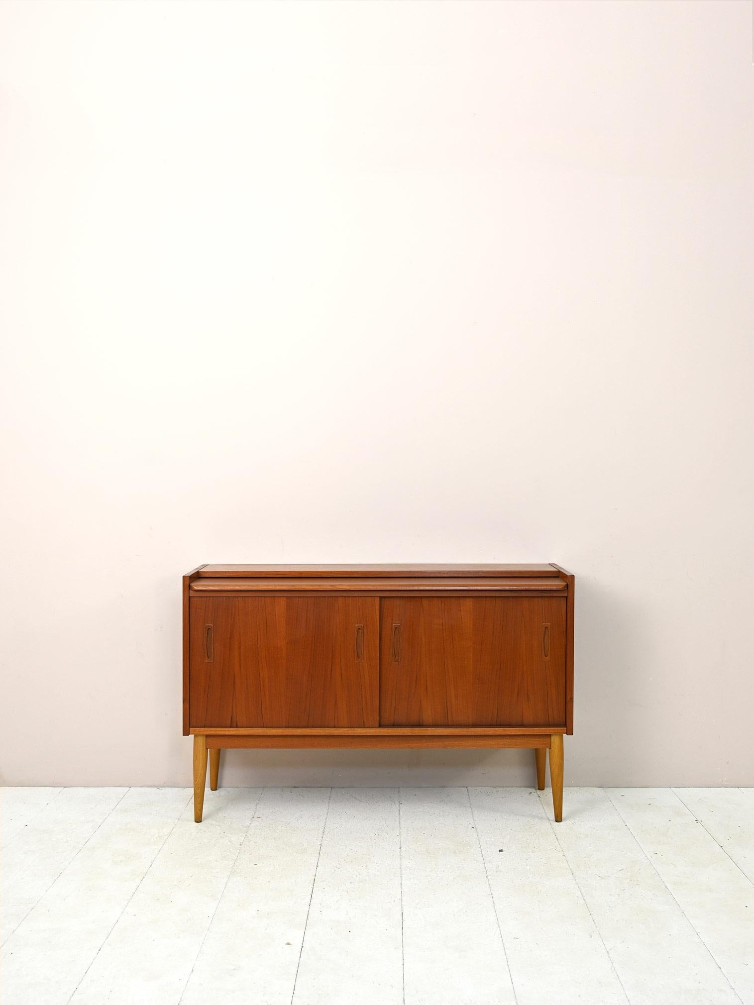 Scandinavian sideboard from the 1960s with drawers and hinged doors.

Particular highboard of Nordic manufacture made of teak wood. Consists of a large storage compartment and 7 drawers of different sizes. The last drawer shares a handle with a
