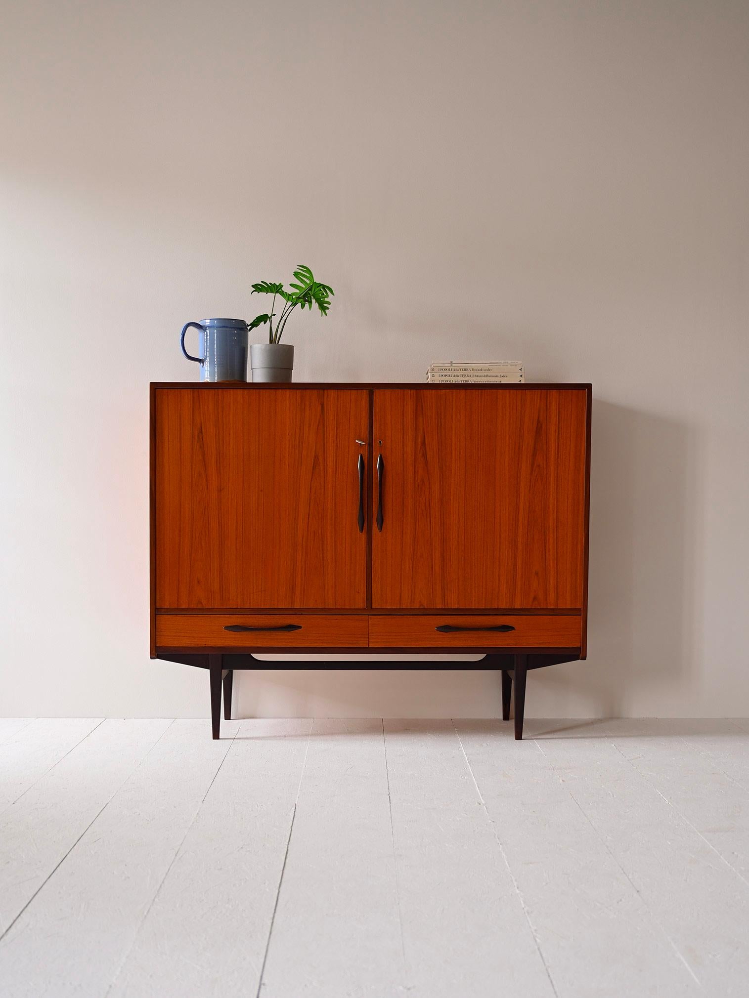 Scandinavian teak sideboard from the 1960s.

This simple yet highly sought-after piece of furniture encapsulates the Nordic tradition for design with essential lines and timeless beauty.
Consisting of two compartments equipped with shelves and