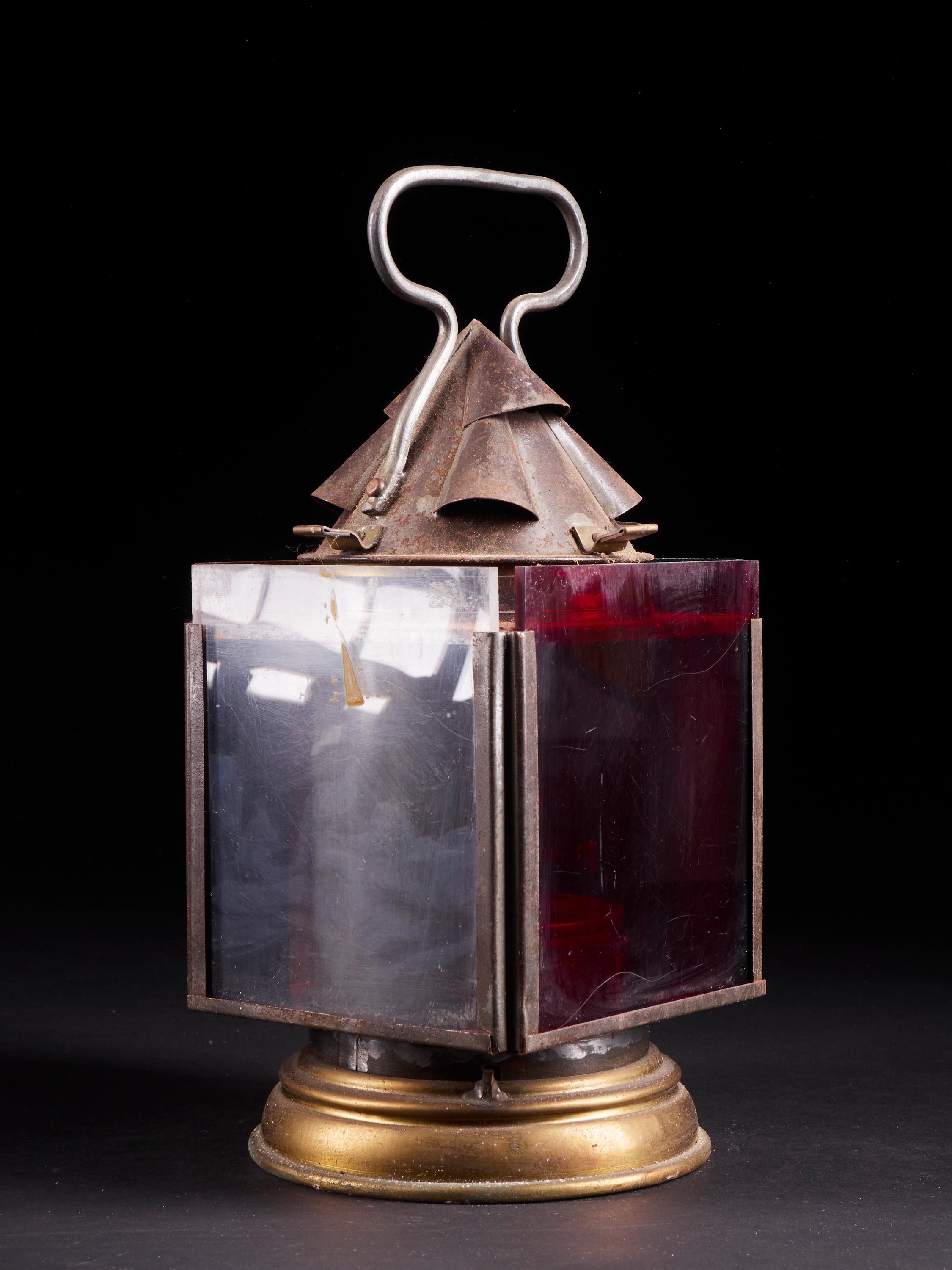 Lovely small vintage square signal oil lantern featuring four orange, blue, red and white tinted glass panels. The lantern has a round brass base and a handle at the top.