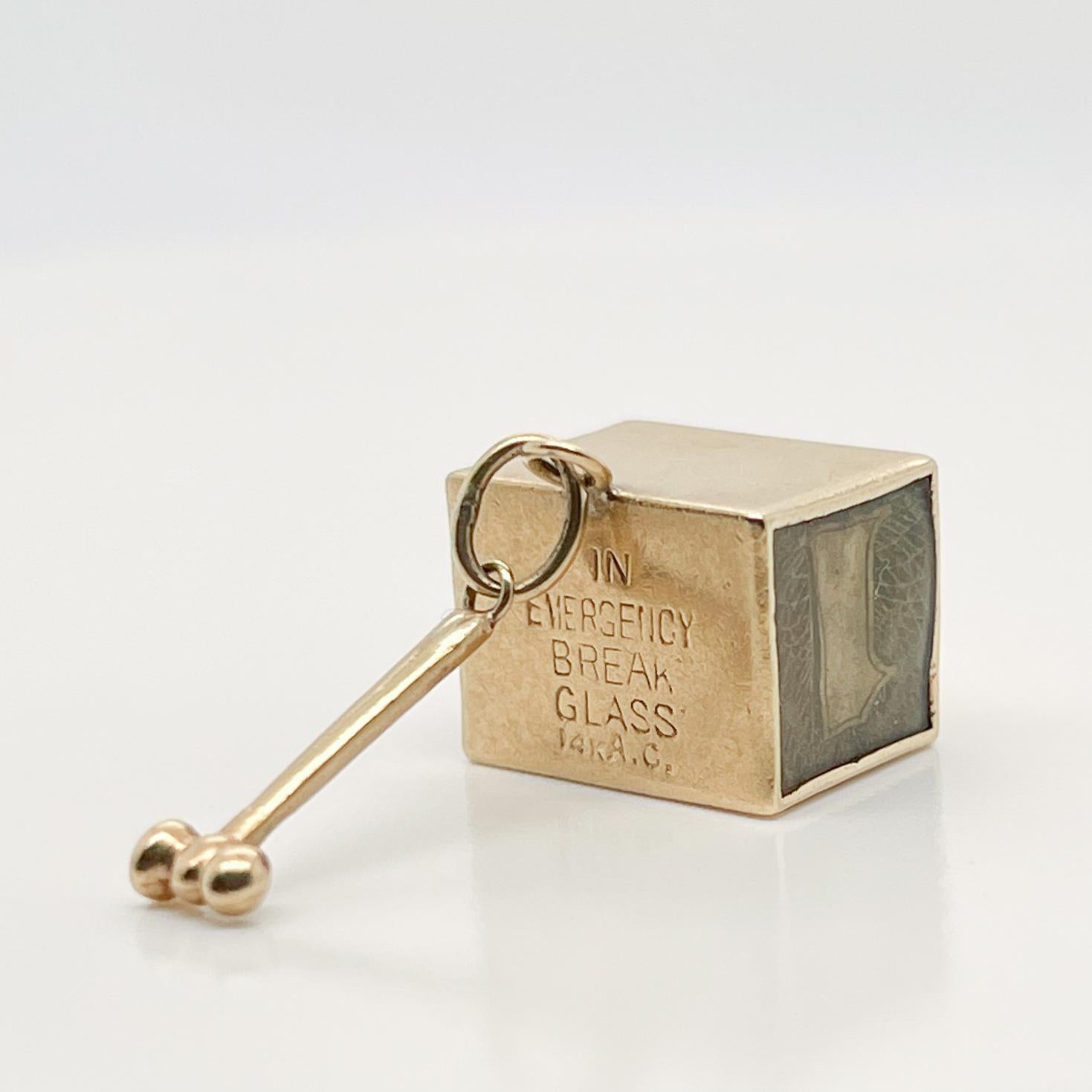 A vintage 14 karat gold charm for a charm bracelet. 

In the form of an emergency box with a dollar inside.  

Inscribed to one side with the message: 