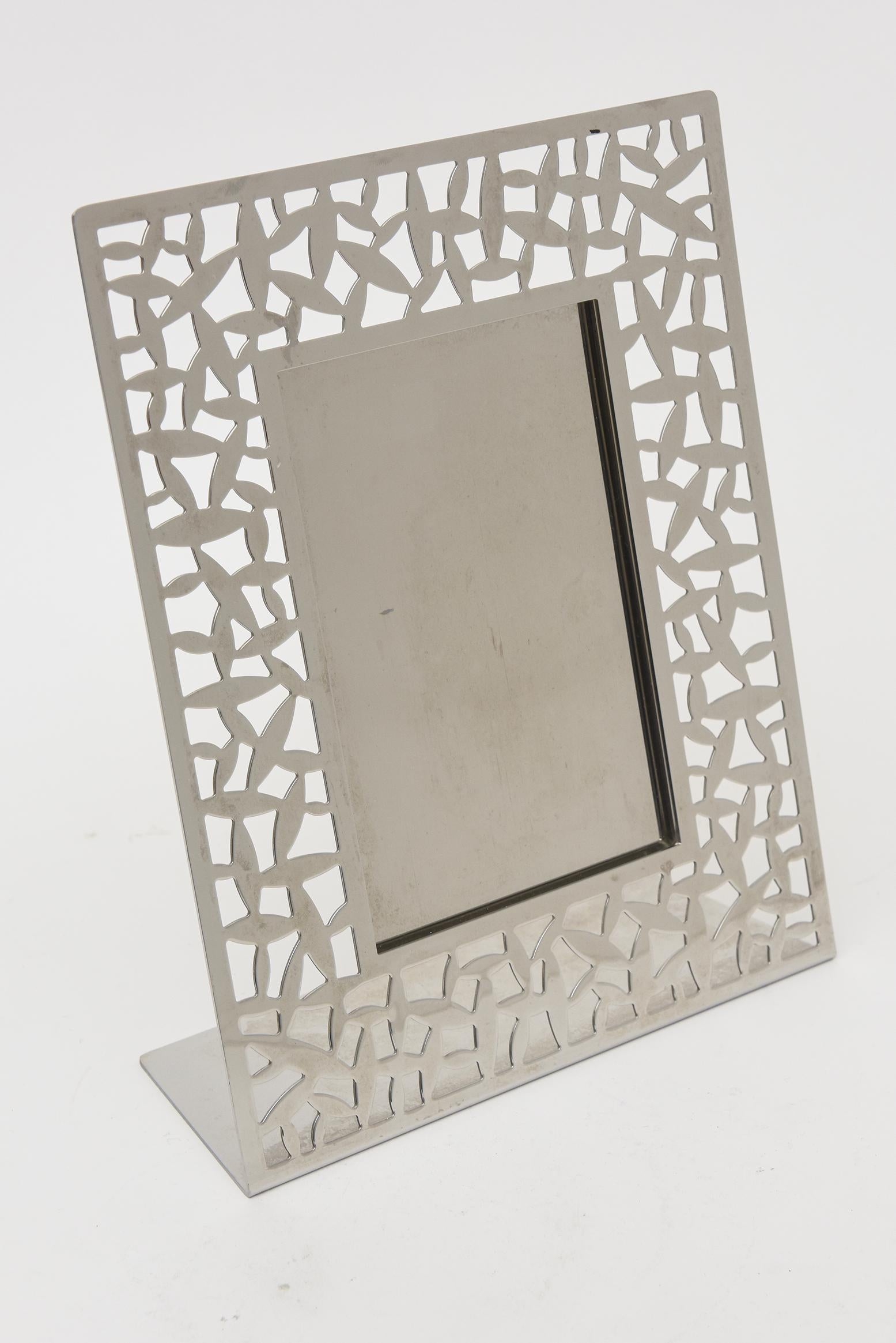 Ce fabuleux cadre photo italien en acier inoxydable d'Alessi est entièrement poinçonné. Le motif, appelé Calle, est moderne et abstrait. Il s'agit désormais d'une pièce abandonnée. On peut y lire Alessi ItalyCSA M Sansoni 2004 Inox 18-10. Depuis