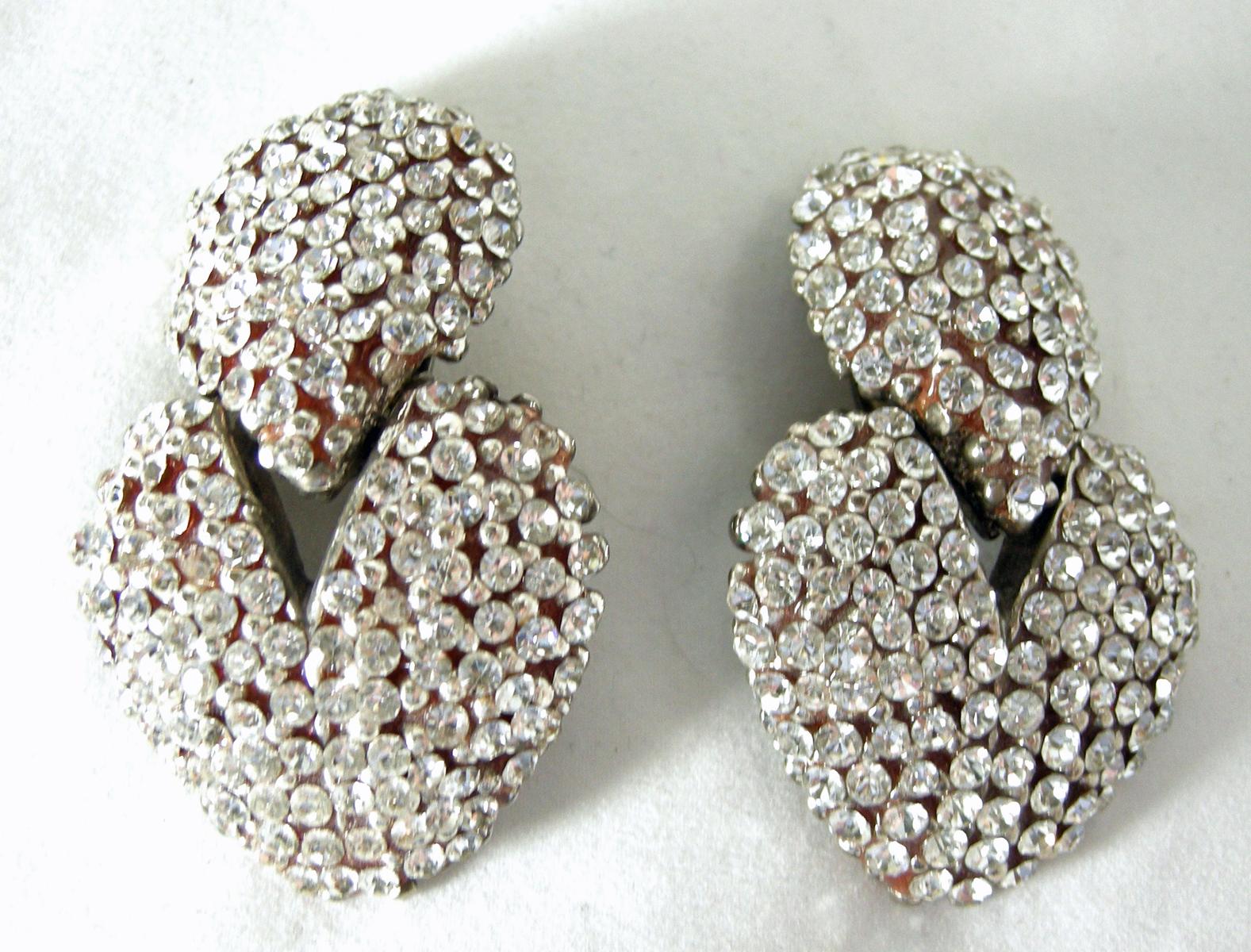 These vintage signed Bellini drop earrings are very dramatic. The tear drop shape top is encrusted with beautiful crystals.  Dangling below is a heart shaped dangle also encrusted with beautiful crystal … all in a silver tone setting.  These clip
