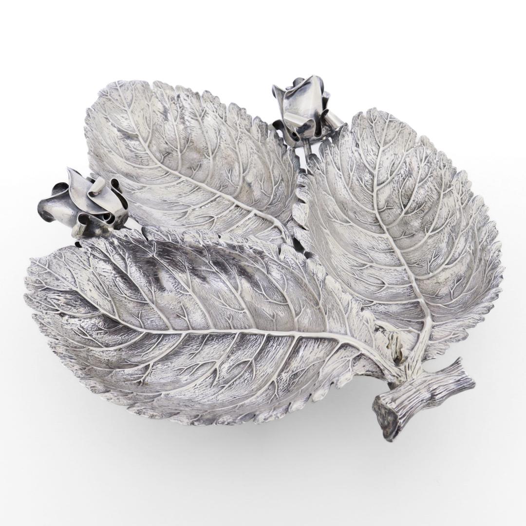 A fine silver centerpiece bowl.

By Buccellati.

In sterling silver.

Designed by Ginamaria Buccellati.

Comprising three rose leaves shaped as bowls and two applied figural rose buds (or flowers) centered on twig-shaped tab handle.

Fully