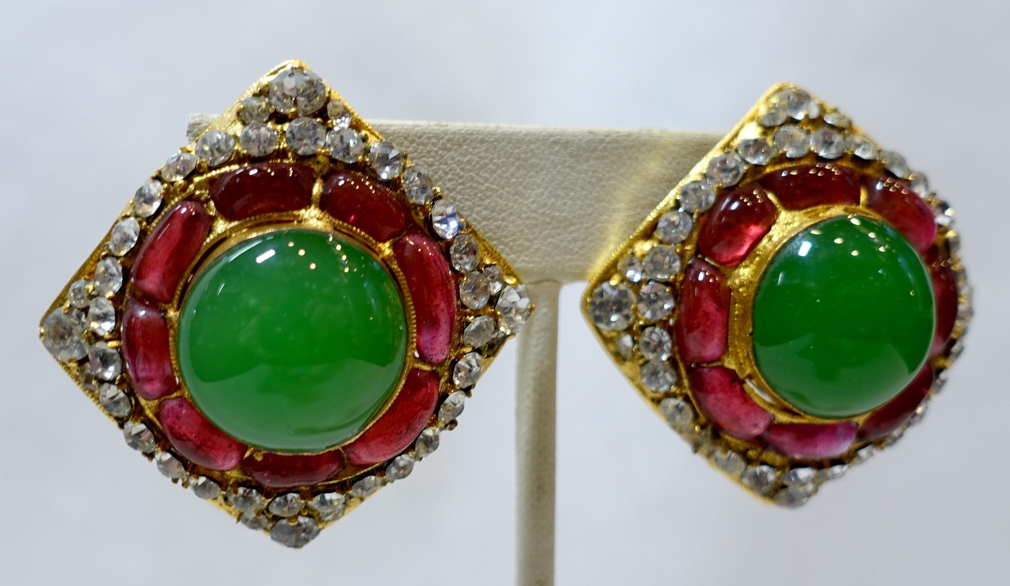 These vintage signed Chanel 26 (1974) earrings feature a center green Gripoix glass cabochon stone accented by cranberry red Gripoix glass stones and brilliant crystals in a gold tone setting.  In excellent condition, these clip earrings measure