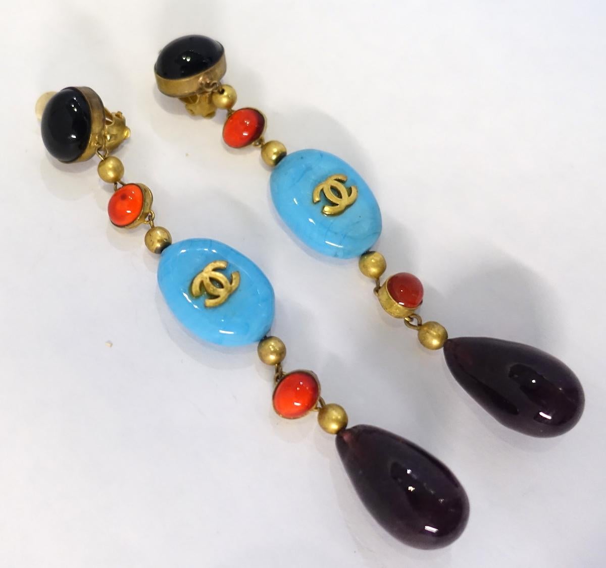These vintage signed Chanel earrings are amazing and looks like they were made for the runway. They have the amethyst color Gripoix button tops. Dangling down is faux coral Gripoix glass and faux turquoise Gripoix with the double “Cs” in the center