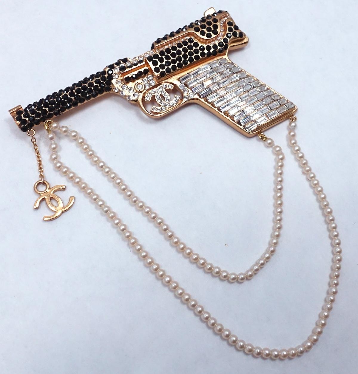 This vintage Chanel runway pistol brooch is one of the most sought after Chanel cuff bracelets. It has crystals throughout with two rows of faux pearls hanging downward and the Chanel CC logo at the end of the pistol.  In excellent condition, this