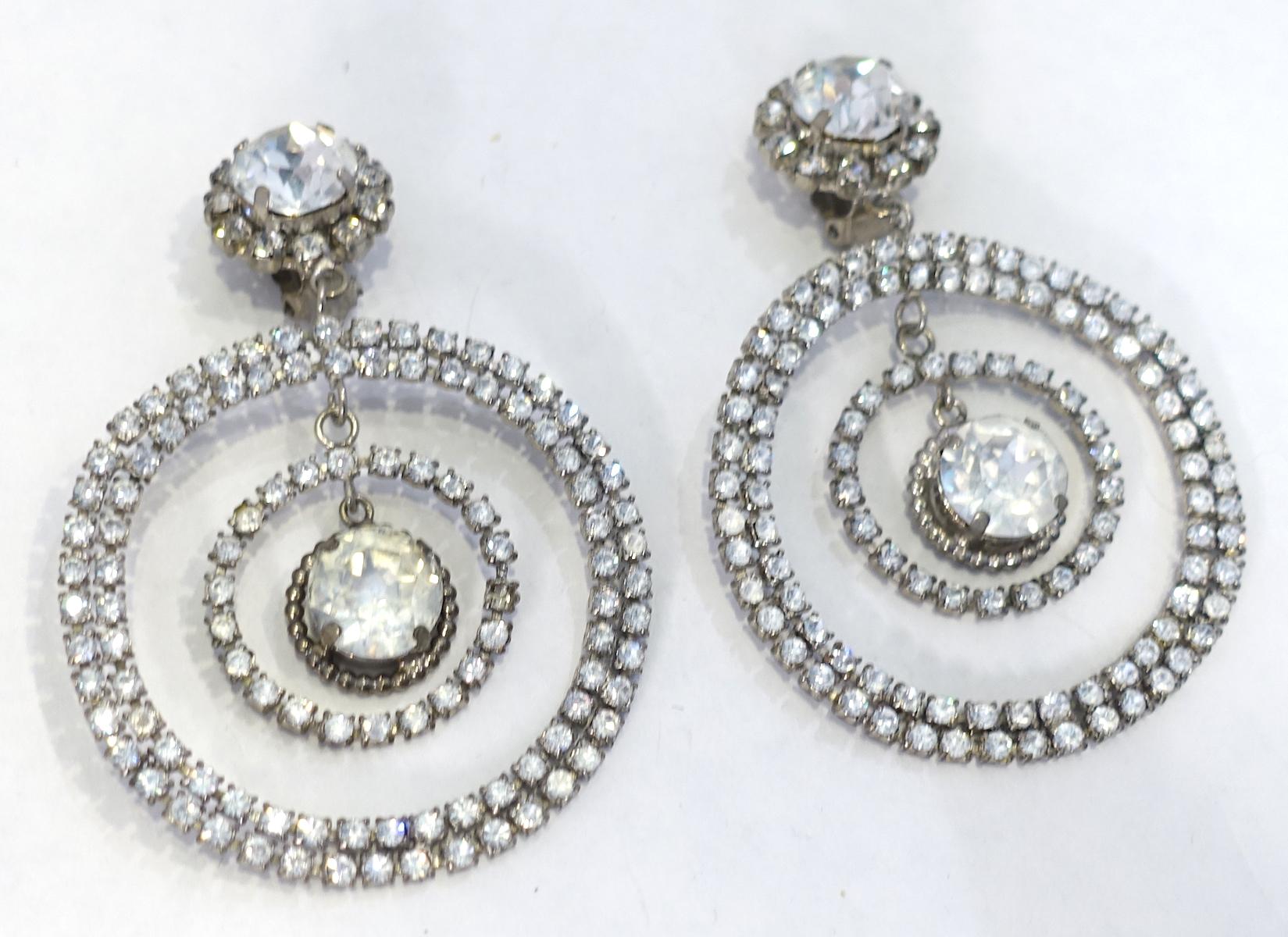These vintage signed Chanel earrings have clear crystals in a double hoop design with a dangling crystal in the center. It is made in a silver tone metal setting.  These clip earrings measure 3-1/2” x 2-1/2” and are signed “Chanel 28 Made in