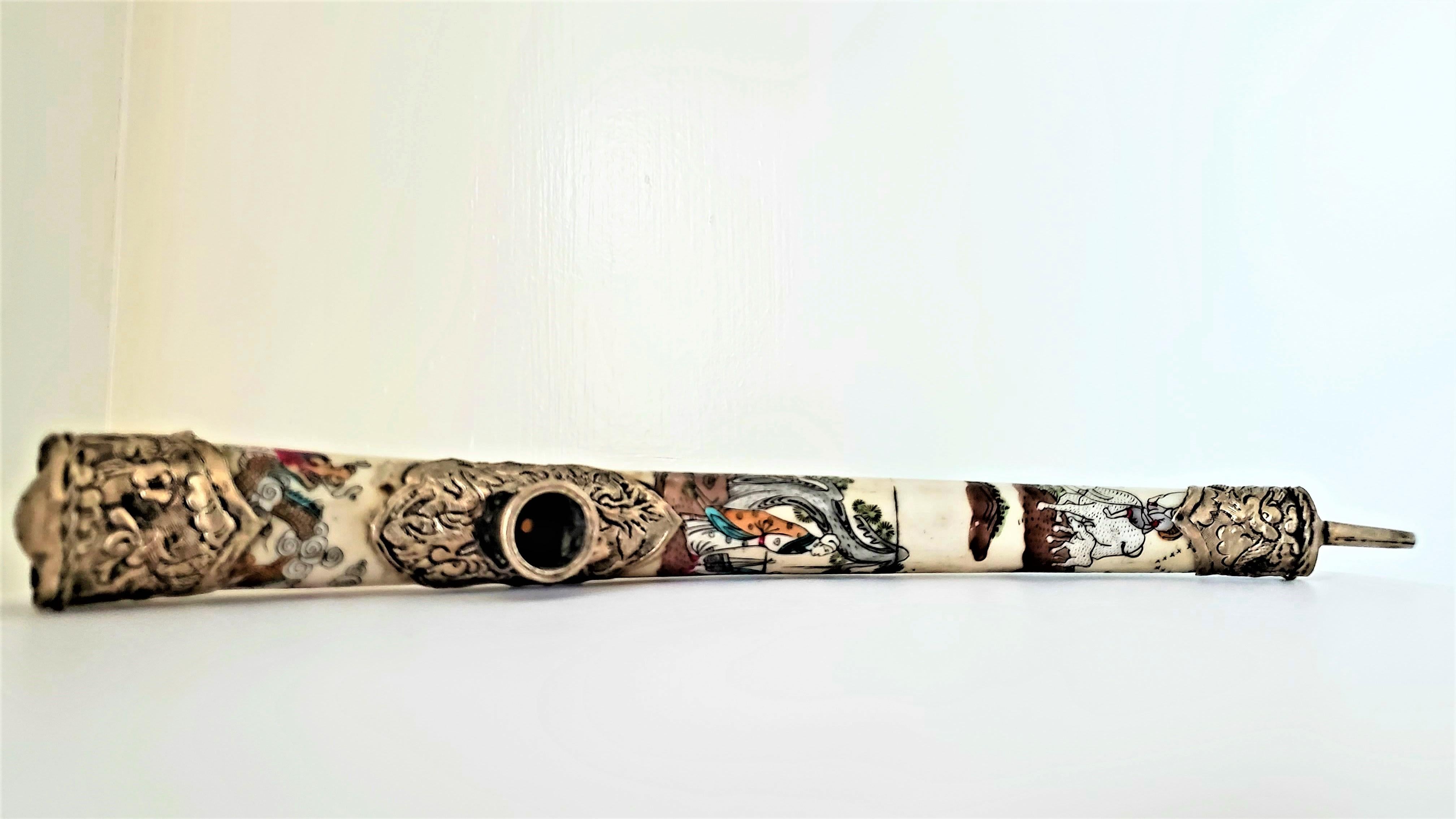 This early to mid 20th century scrimshaw opium pipe is made of bone with with silver metal detailing. The scrimshaw is finely done with vibrant colours depicting agrarian scenes and the auspicious dragon. The pipe is signed by the maker and I would