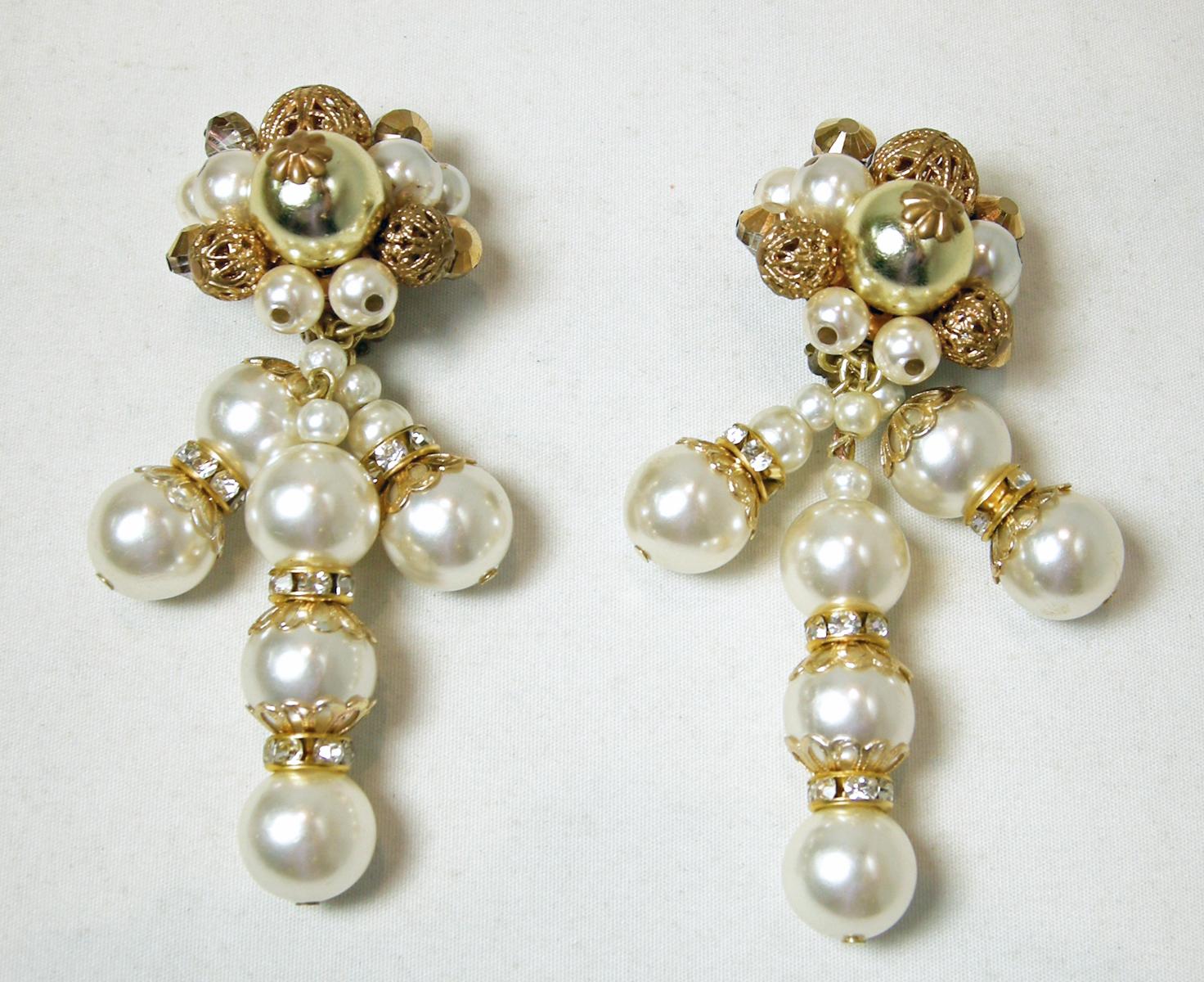 These vintage signed DeMario earrings feature faux pearls with gold tone filigree balls on top. There are pearl drops with crystals accents.  In excellent condition, these clip earrings measure 3” x 1” and are signed “DeMario.”.