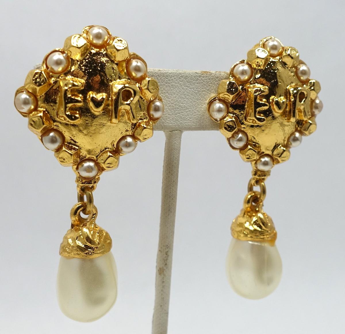 These vintage signed Edouard Rambaud earrings have faux pearls on a gold tone setting with the initials “E R” in the middle of the top with gold tone beading on the outside. A faux pearl hangs down.  In excellent condition, these clip earrings