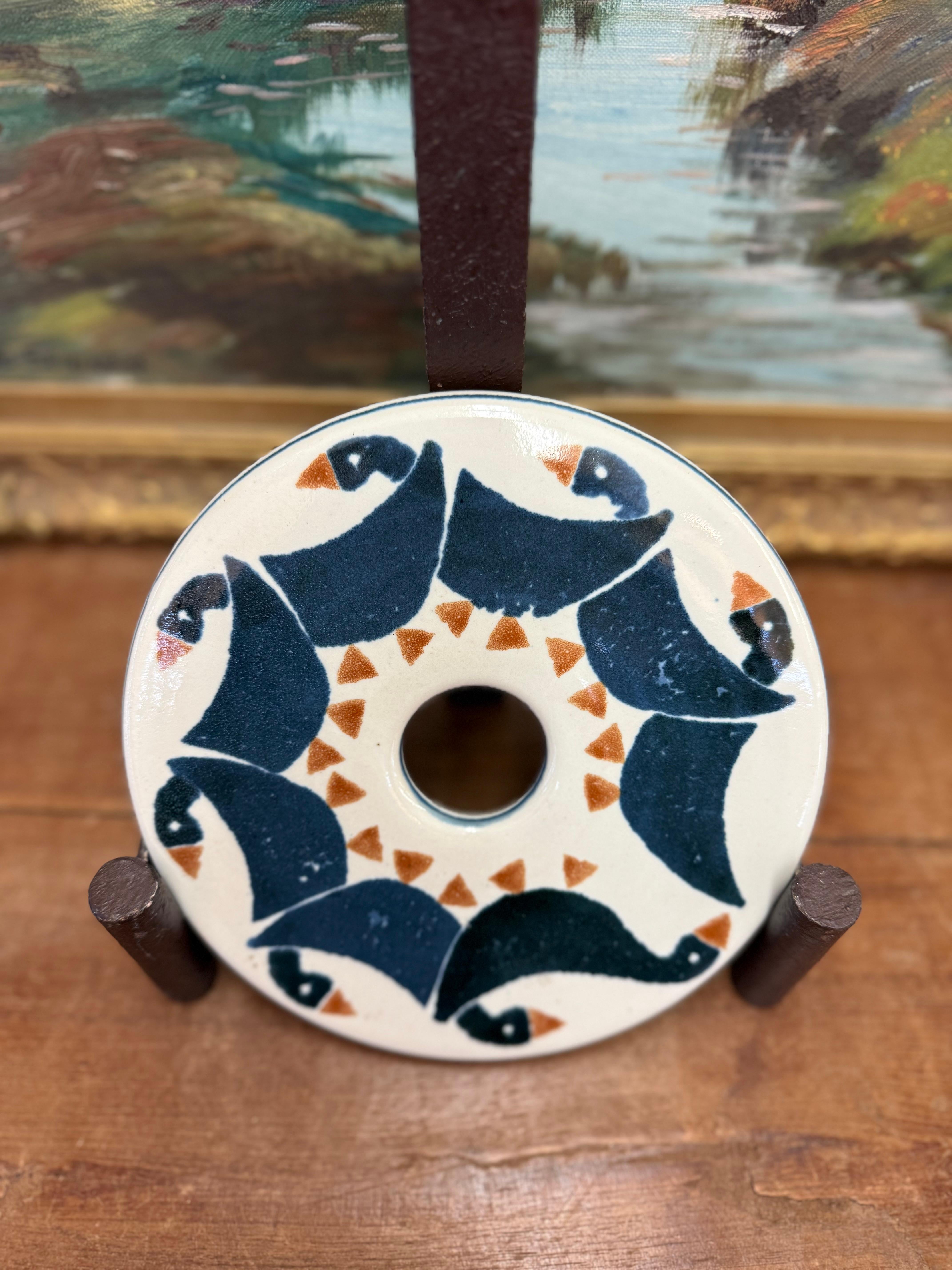 Esta cerámica hecha a mano es una pieza bellamente elaborada que combina la funcionalidad con el encanto artístico. El diseño presenta un motivo repetido de patos estilizados en azul marino intenso con toques de color terracota sobre un fondo blanco