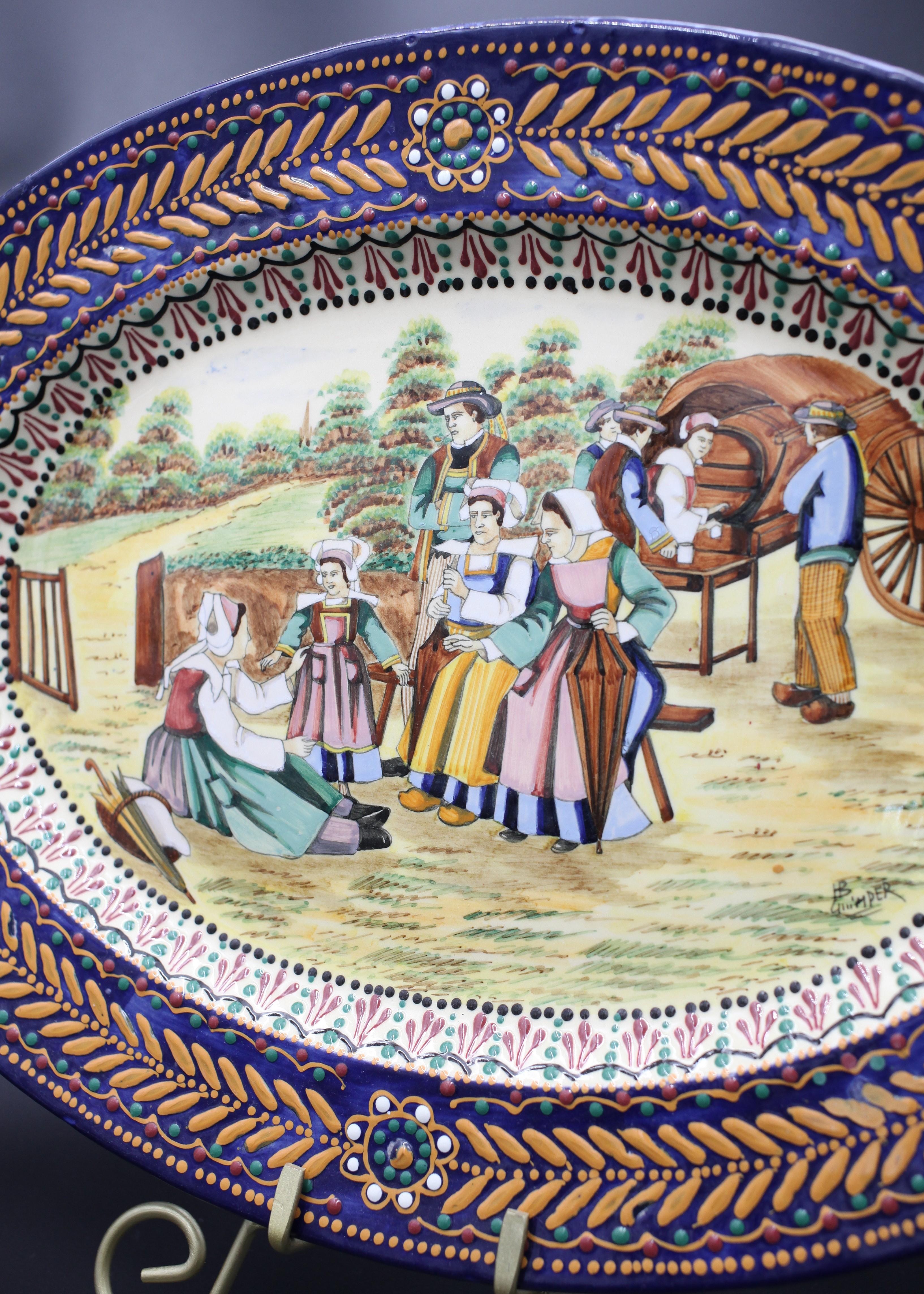 Diese elegante Platte mit ihren leuchtenden Farben aus der renommierten französischen Keramikmanufaktur HB Quimper ist ein Zeugnis für den Charme des Art déco des frühen 20. Jahrhunderts. Die ovale Platte ist mit einem komplizierten Broderie-Muster