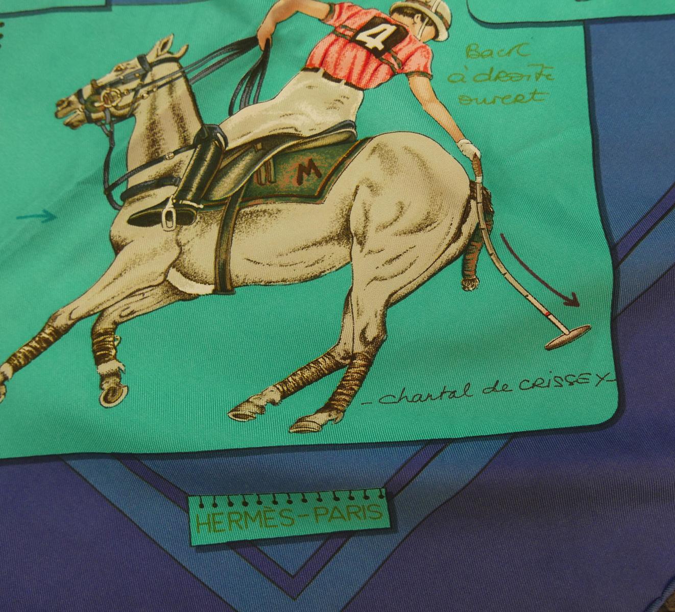 This vintage signed Hermes scarf features “Le Monde du Polo”, originally designed by Chantal de Crissey, depicting various notated polo scenes with blue and turquoise background.  In excellent condition, this scarf measures 35” square and is signed