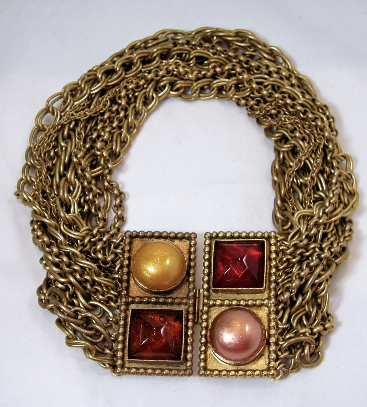 This is a gorgeous Isabel Canovas necklace that incorporates 12 different chains that lead to two squares on each end creating an oblong ribbed design. On one side is Gripoix topaz color glass along with a yellow dome.  The other side has red