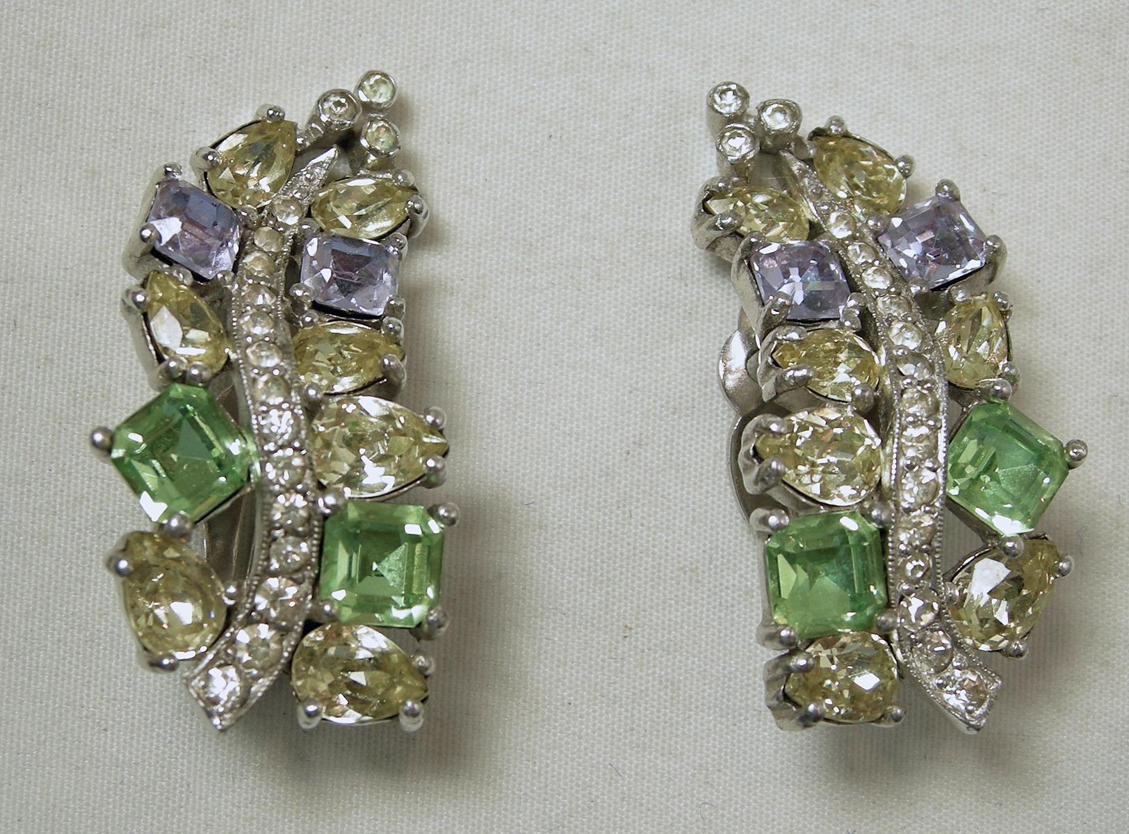 These vintage signed Jomaz earrings feature peridot green, citrine, blue and clear crystals in a rhodium silver tone setting.  In excellent condition, these clip earrings measure 1-3/8” x ¾” and are signed “Jomaz”.