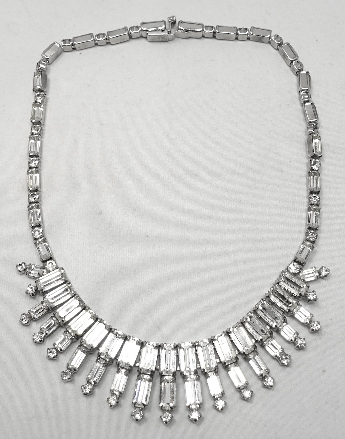 This vintage signed Kramer necklace has clear crystals in a rhodium silver tone setting.  In excellent condition and signed “Kramer”, this necklace measures 15” with a slide in clasp x 1” at front/center.
