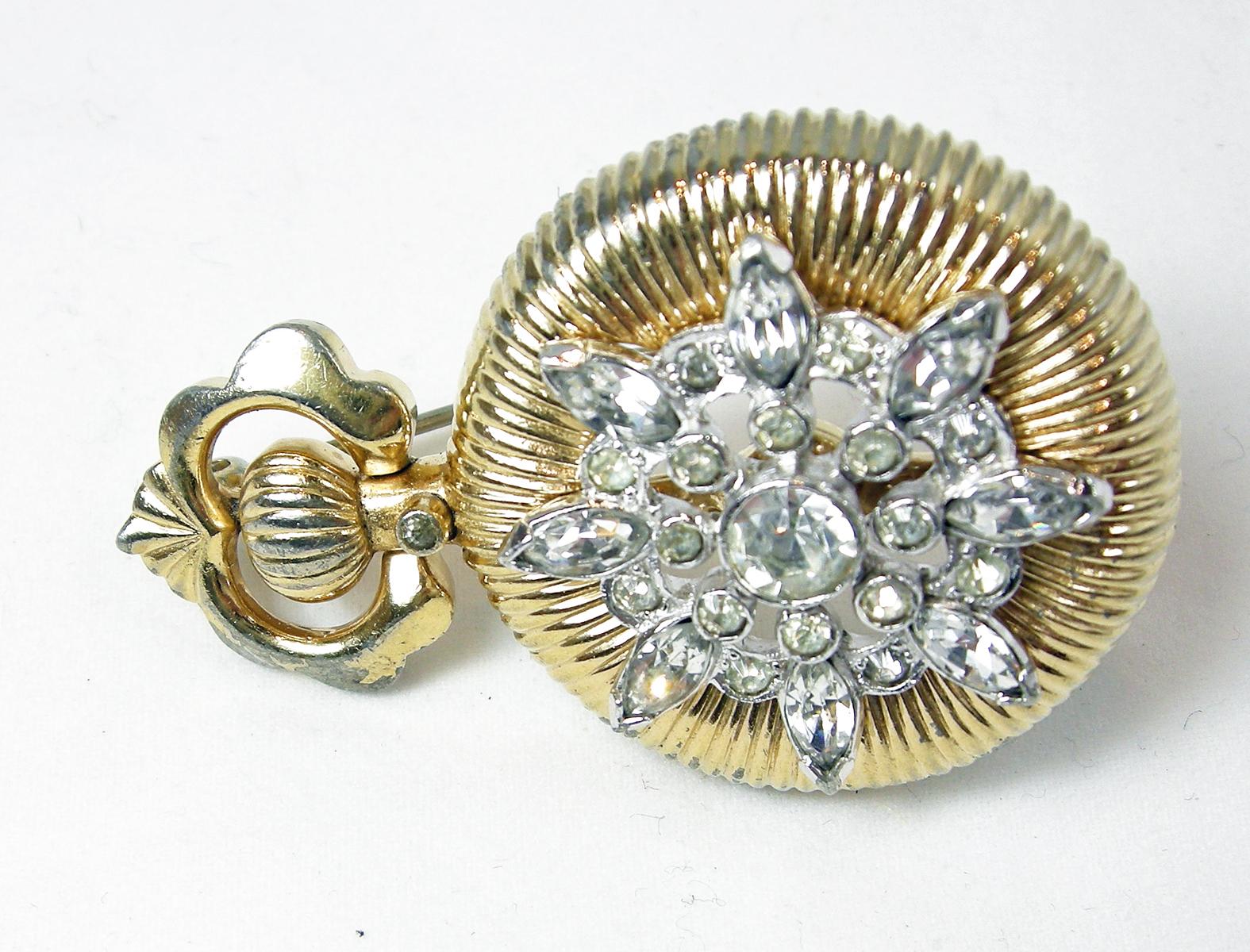 This vintage Mazer set was created to look like clock in a gold tone setting.  Clear crystals in a starburst design adorn the center of the brooch and earrings. The brooch measures 2” x 1-1/4” and the matching clip earrings are 1-1/4” x 3/4”.  It is