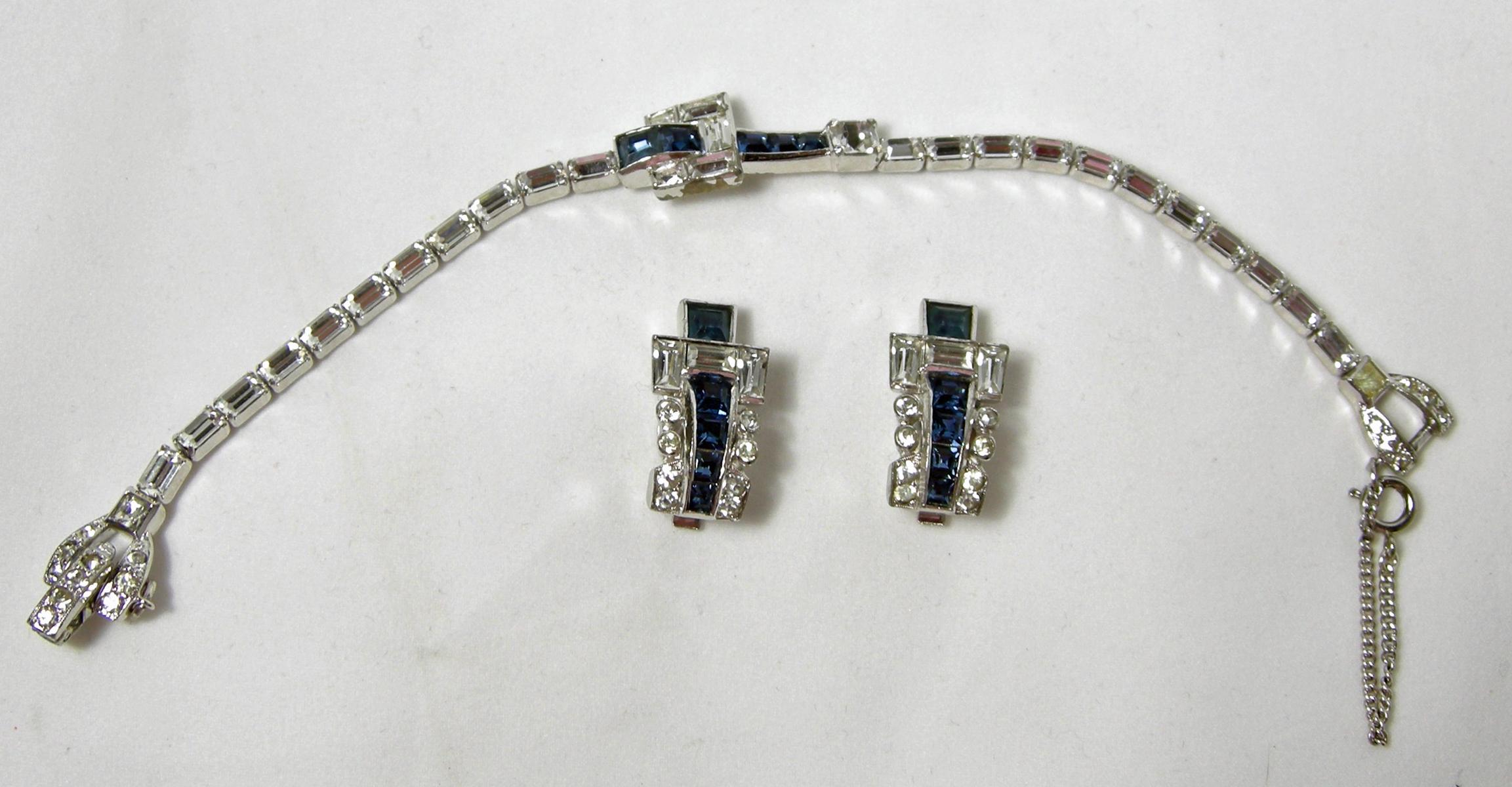 This amazing Mazer set looks real.  It has crystal links leading to the center design of a faux sapphire buckle.  It has a fold over clasp in a silver tone rhodium setting.  It is signed “Mazer Bros.” It measures 7” long.  The buckle is 1” x 1/2