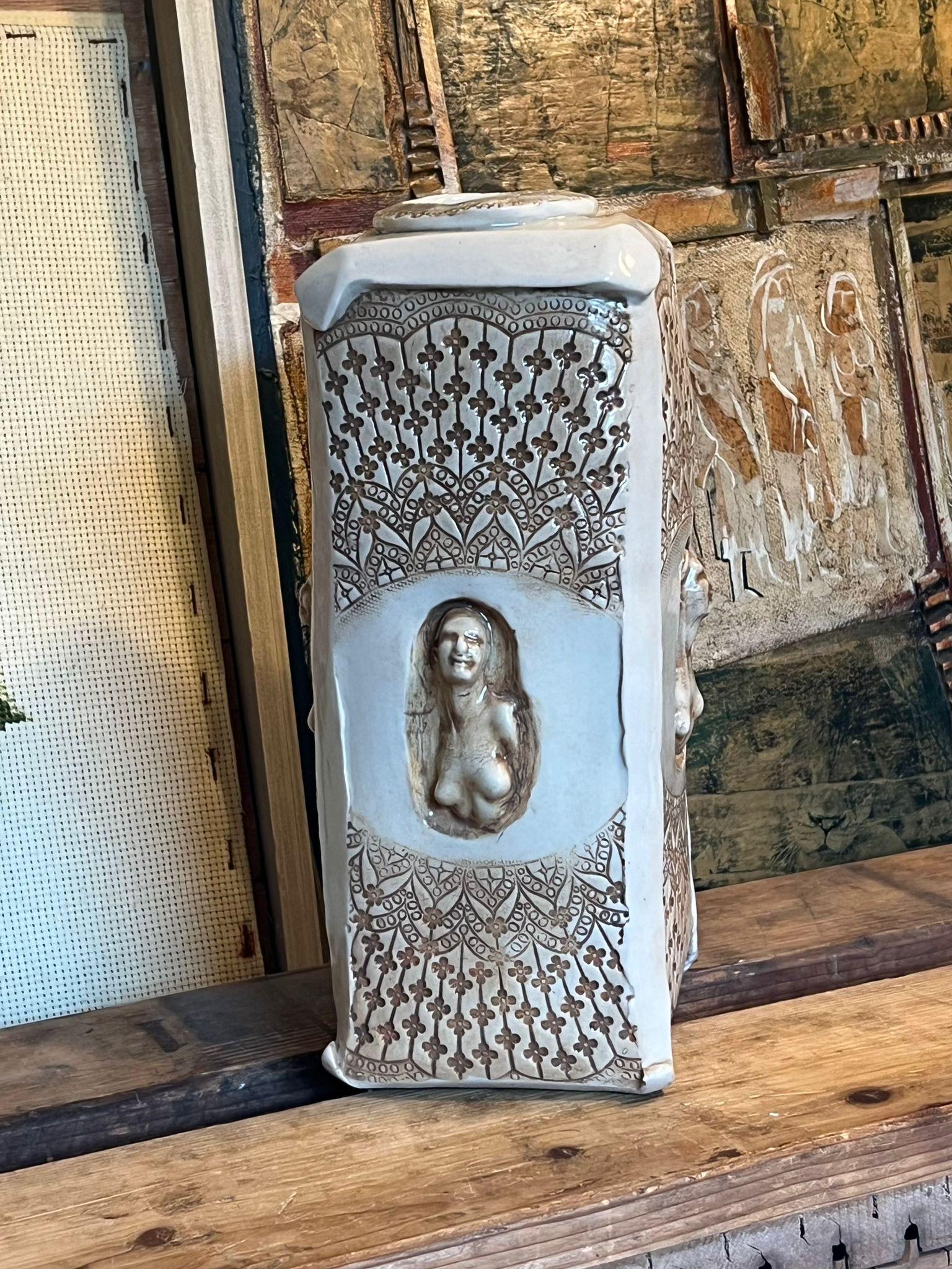 Questo pezzo vintage di MCM è una creazione in studio Pottery fatta a mano e firmata con intagli e timbri unici. Presenta una texture floreale e figure femminili su ogni lato dell'esterno beige, altrimenti neutro. È un pezzo robusto che può essere