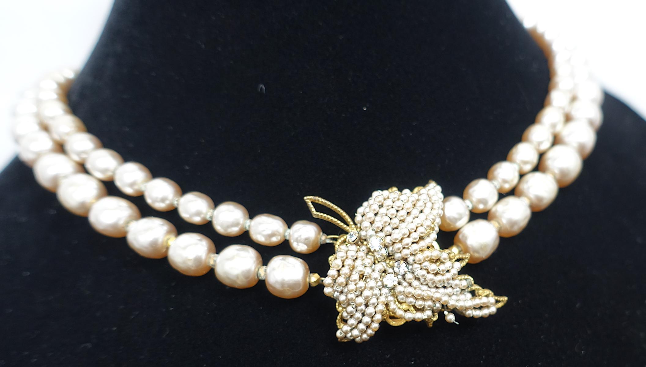 This vintage signed Miriam Haskell necklace has a leaf design encrusted with faux seed pearls. It has two strands of faux pearls in a gold tone setting.  This necklace measures 15-1/4” with a slide-in clasp. The leaf is 1-5/8” x 1-1/4”.  In