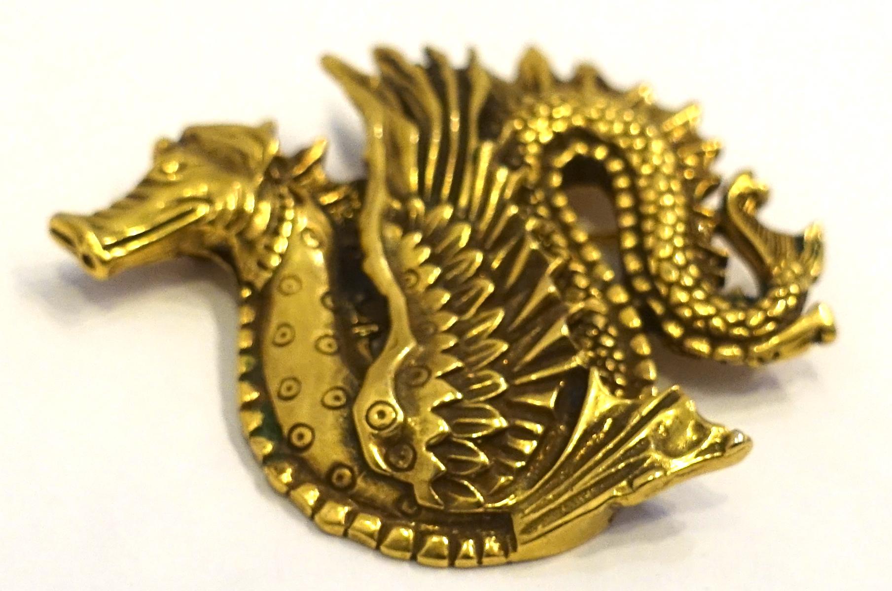 This vintage brooch is from the Museum of Modern Art and depicts a heavily carved dragon in a gold tone setting.  In excellent condition, this brooch measures 2-1/2” x 2” and is signed “MMA”.