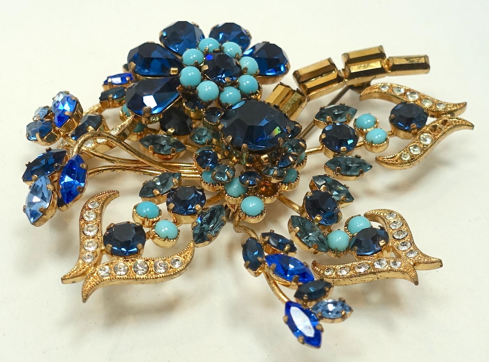 This vintage signed Model Maryse Blanchard Paris brooch has a floral design with blue, turquoise and clear crystals in a gold tone setting.  In excellent condition, this brooch measures 3” x 3” and has two signatures …  “Made in Austria” and “Model