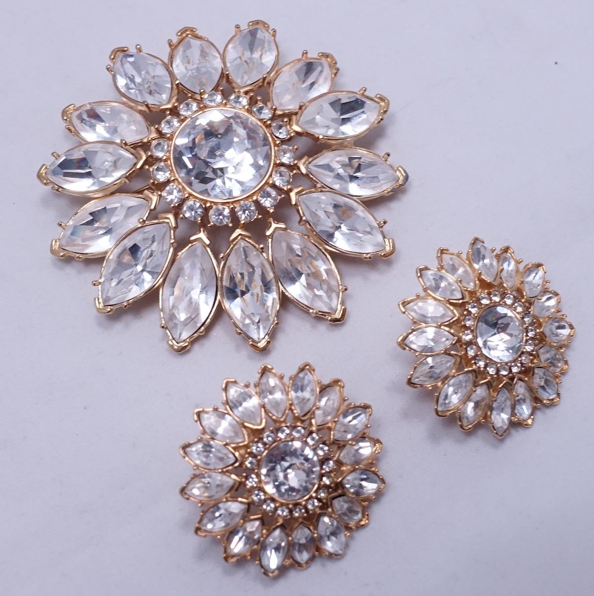 This vintage Monet set features clear crystals in a gold tone setting.  The brooch measures 2-3/4” in diameter and the matching clip earrings measure 1-1/4”.  It is signed “Monet” and it is in excellent condition.
