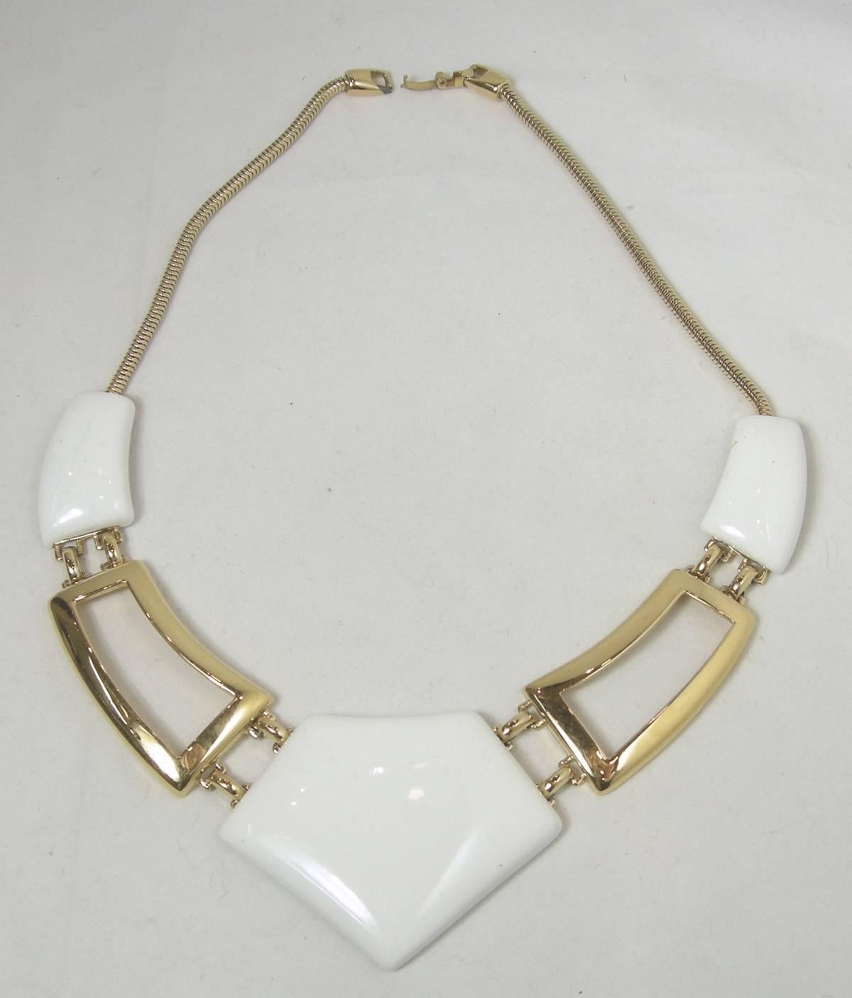 This Monet necklace is perfect for the summer.  It has a snake chain with a fold over clasp.  There are two curved white enamels elongated ovals attached to gold tone open work that attaches the white enamel centerpiece.  The necklace is 16” and the