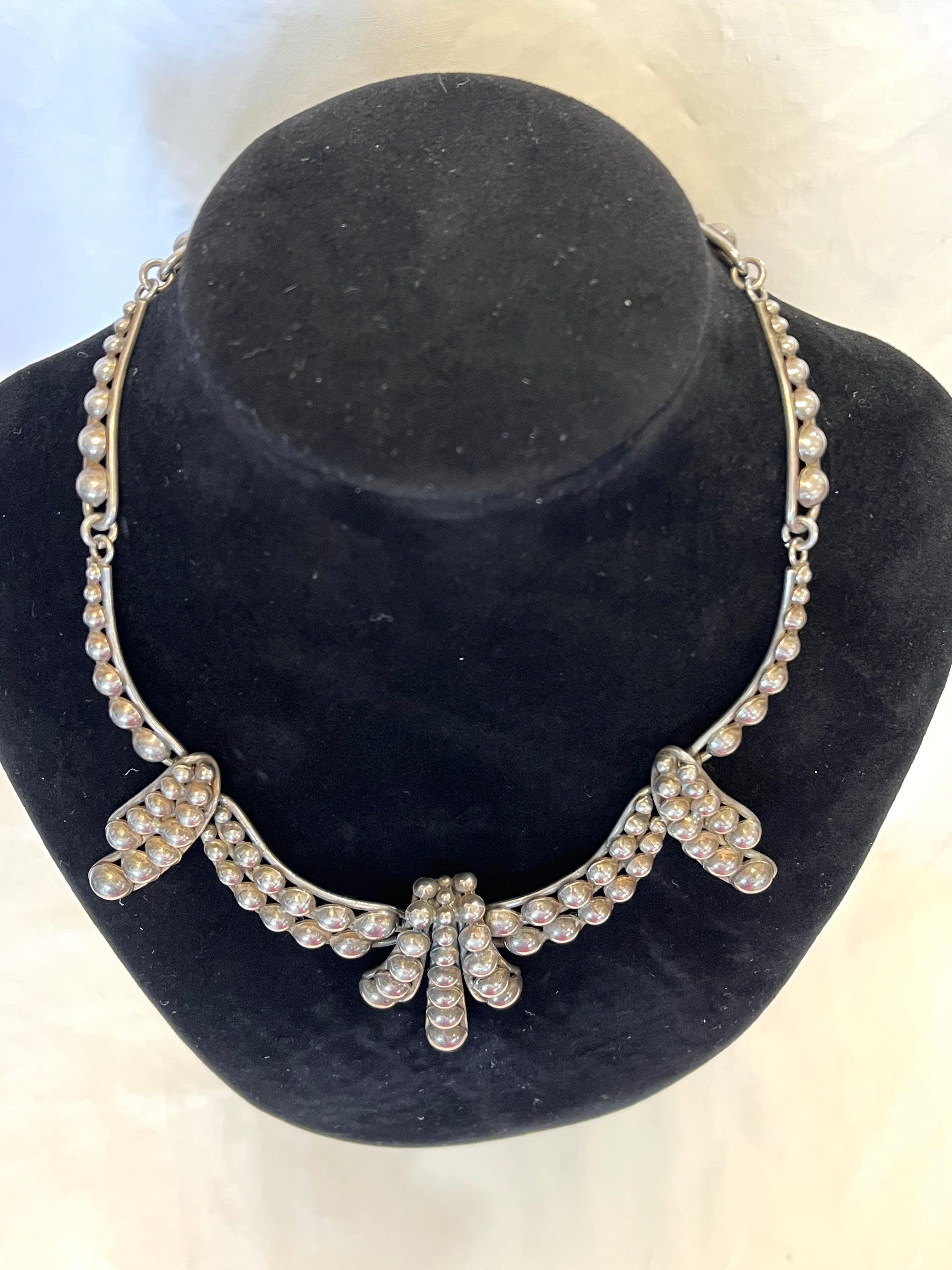 A beautiful and bold statement necklace in sterling silver by Napier. The half spheres are nestled together in further organic, playful forms that when presented on the neck create almost a choker or collar style necklace. The Napier Company, as