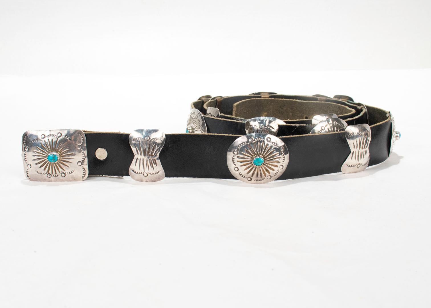 A fine vintage Navajo belt.

By Jimmy Herald.

Consisting of a leather belt with sterling silver 'conchos' (shells) and turquoise accents. The slides are copper backed and there are 18 conchos in total with 9 bowtie shaped, 8 oval shaped, and 1 as