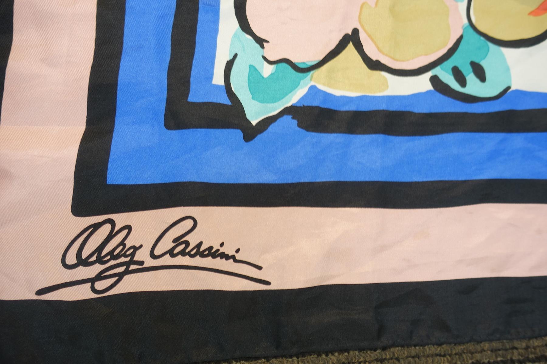 This vintage signed Oleg Cassini scarf features a floral design in hues of pink, coral, turquoise, blue, black and beige.  This scarf measures 35” x 34-1/2” and is signed “Oleg Cassini”.