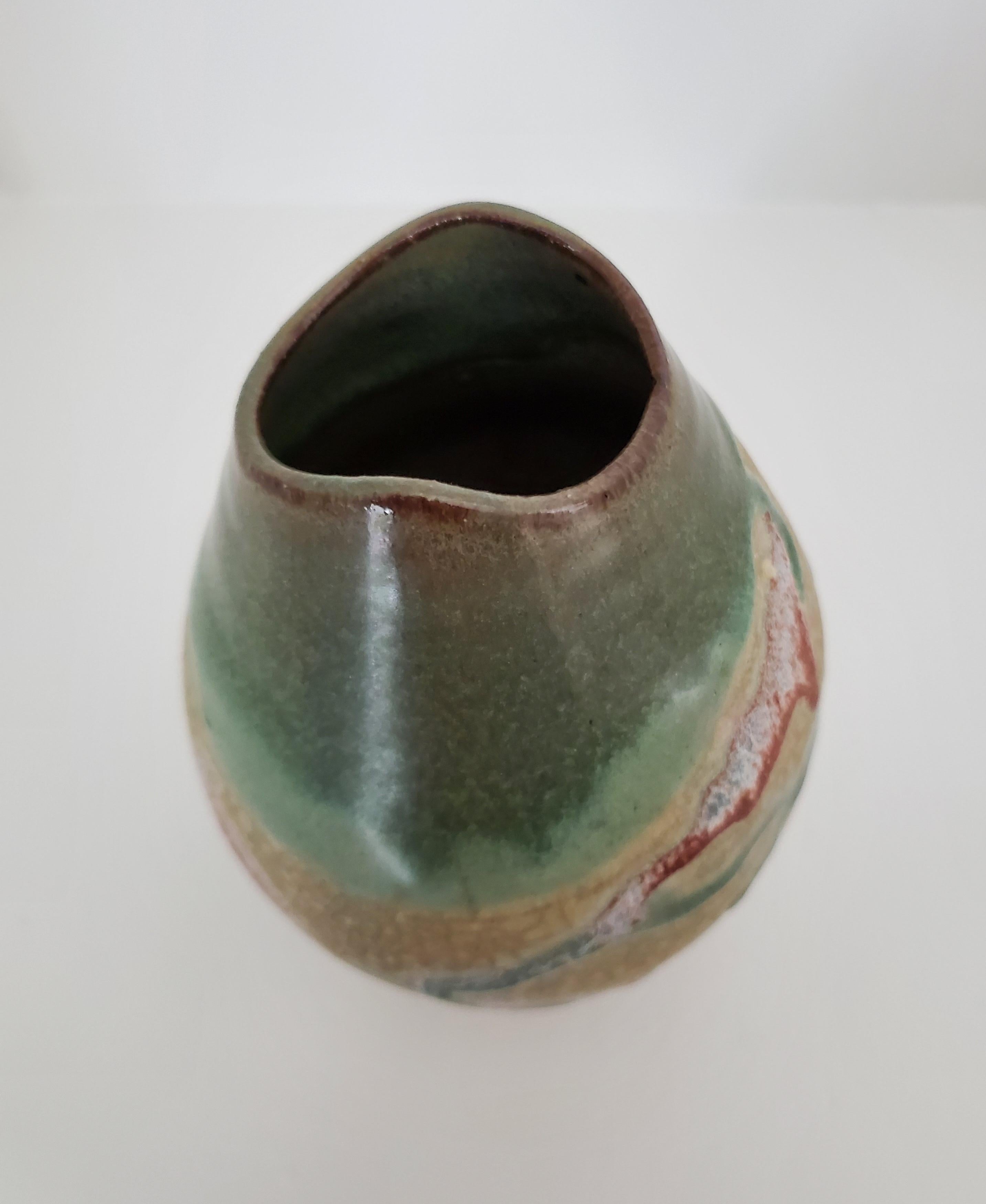 This vintage raku terracotta pottery vase is a delight to the eyes and a pleasure to handle. The unglazed taupe crackled background is rough to the feel and is embellished with smooth, raised glazed black, brick, brown, and aqua overlay. The mouth
