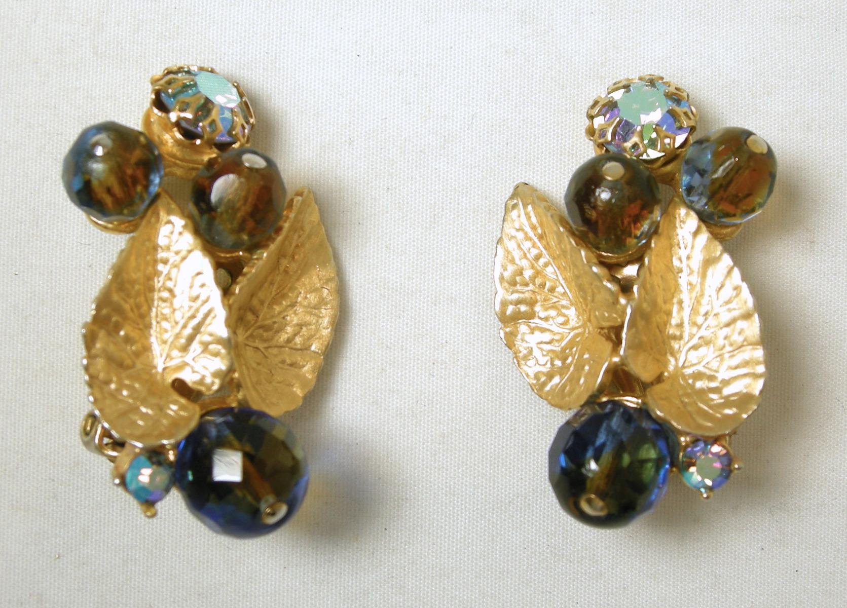 These vintage signed Schiaparelli earrings have gold tone leaves with multi-color Aura Borealis stones streaming out on both ends.  In excellent condition, these clip earrings measure 1-1/2” x 1” and are signed “Schiaparelli”.