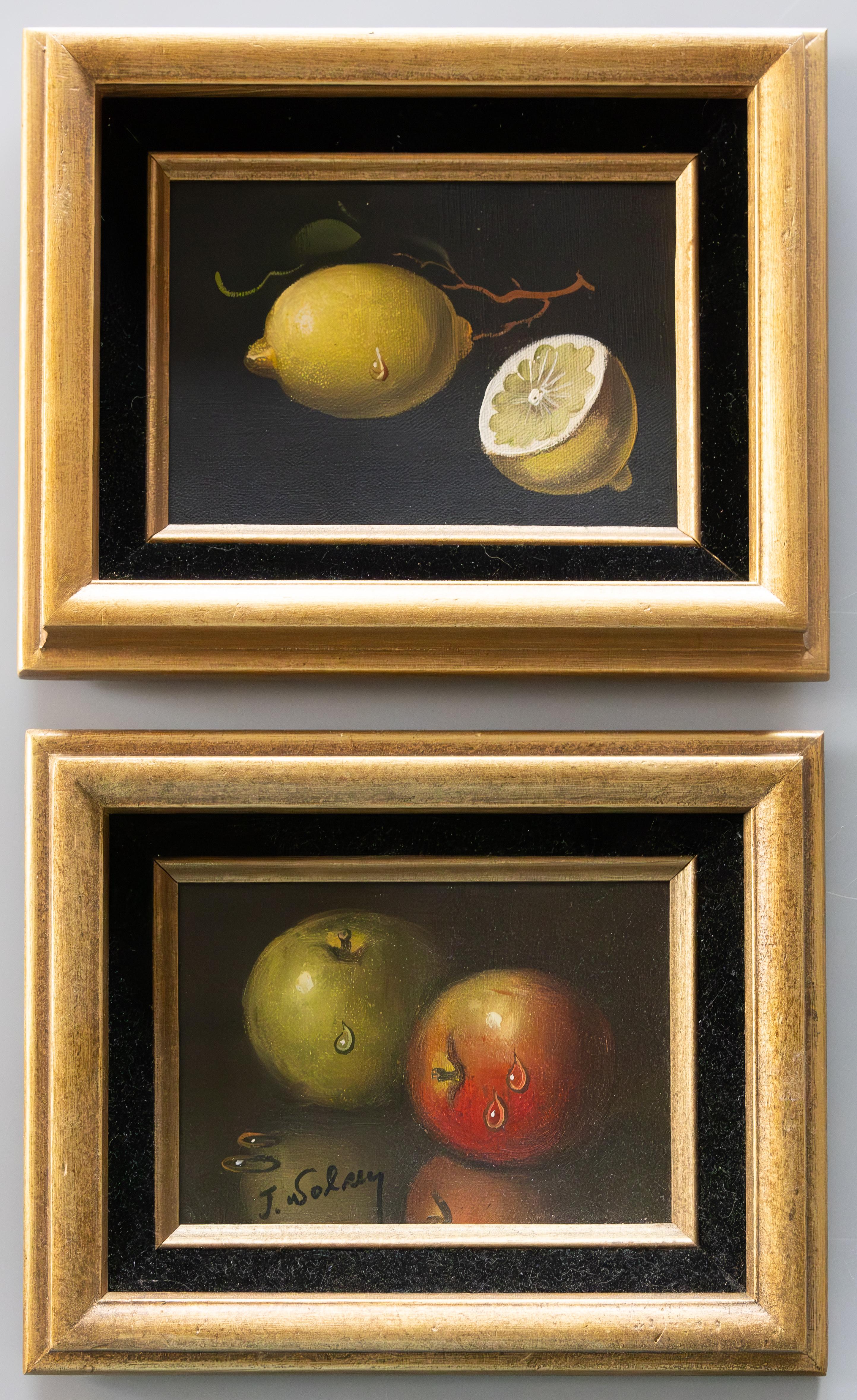 Lovely pair of paintings depicting glistening lemons and apples. Oil on canvas with a board back. The painting with apples is signed, signature indistinct.  Frames are inset with black velvet and lightly guilded. Painting itself measures 5