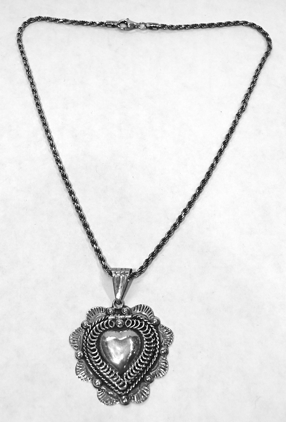 This vintage signed Taxco Mexico sterling silver locket features a heart design that open in the front and is suspended on a sterling silver rope link chain.  The locket measures 1-1/2” x 1-3/8”; the chain measures 16” long with a spring closure x