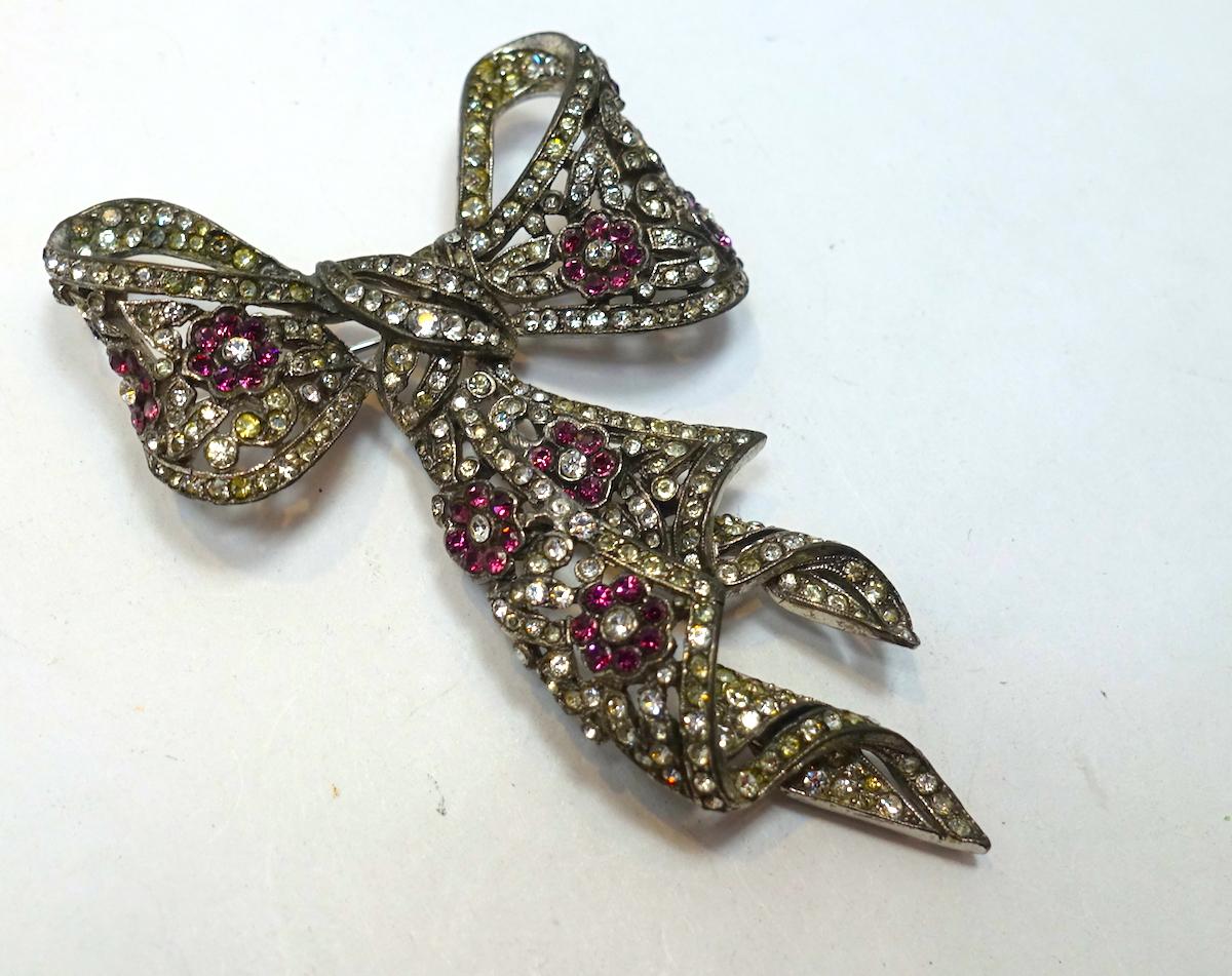 This highly collectible vintage signed Trifari bow brooch has been featured in many costume jewelry books.  This flowing bow has clear and pink crystals in a silver tone setting.   In excellent condition, this brooch measures 3” x 2” and is signed