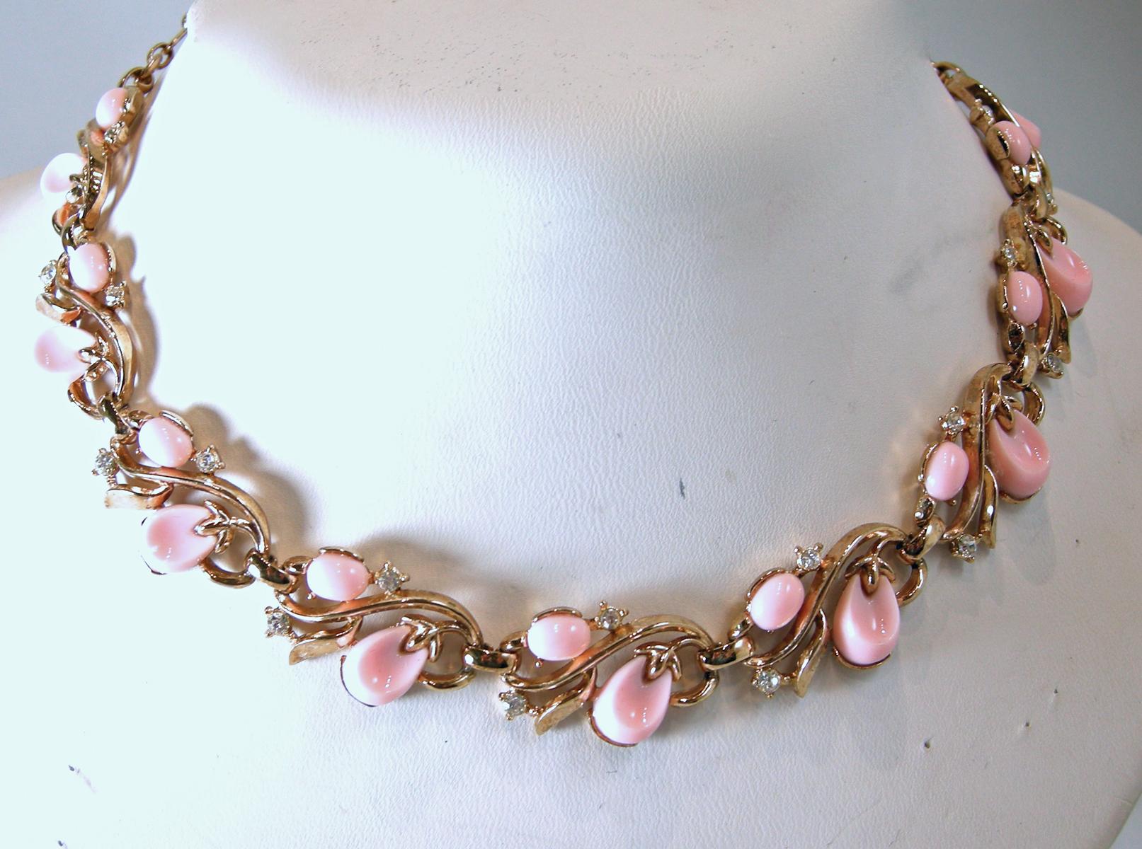 This vintage signed Trifari set has the necklace, bracelet and earrings with pink stones and clear crystal accents in a gold tone setting.  The necklace measures 15-1/2” x 5/8” with a hook clasp.  The matching bracelet is 7” x 5/8” with a fold-over