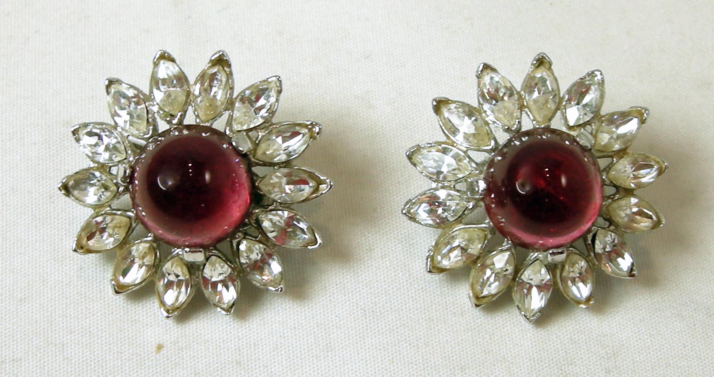 These vintage signed Trifari earrings have a red crystal center with clear crystals surrounding it.  It’s in a silver tone setting.  In excellent condition, these clip earrings measure 1” and are signed “Trifari”.  They are in excellent condition.